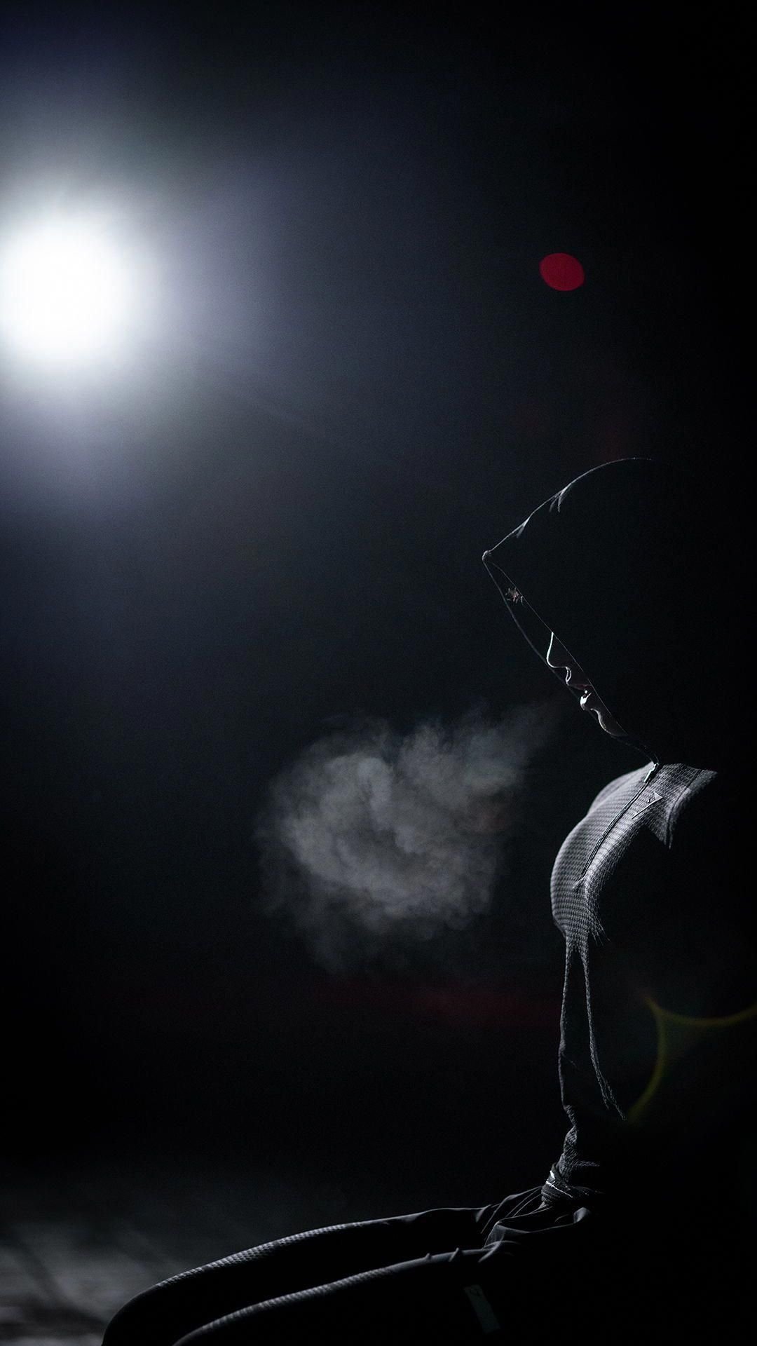 A person sitting in the dark with smoke coming from their mouth - Gym