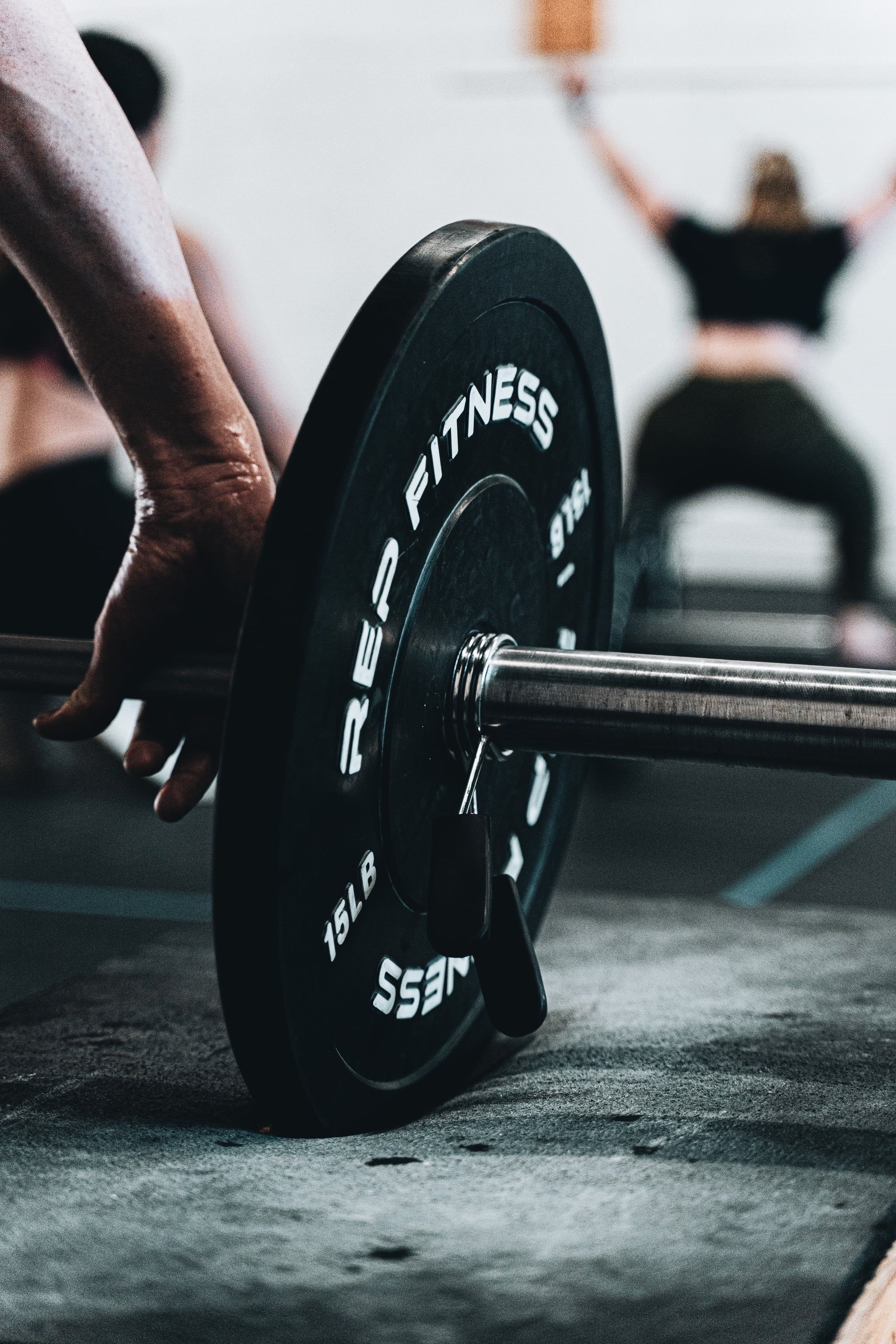 A person picking up a barbell from the floor - Gym