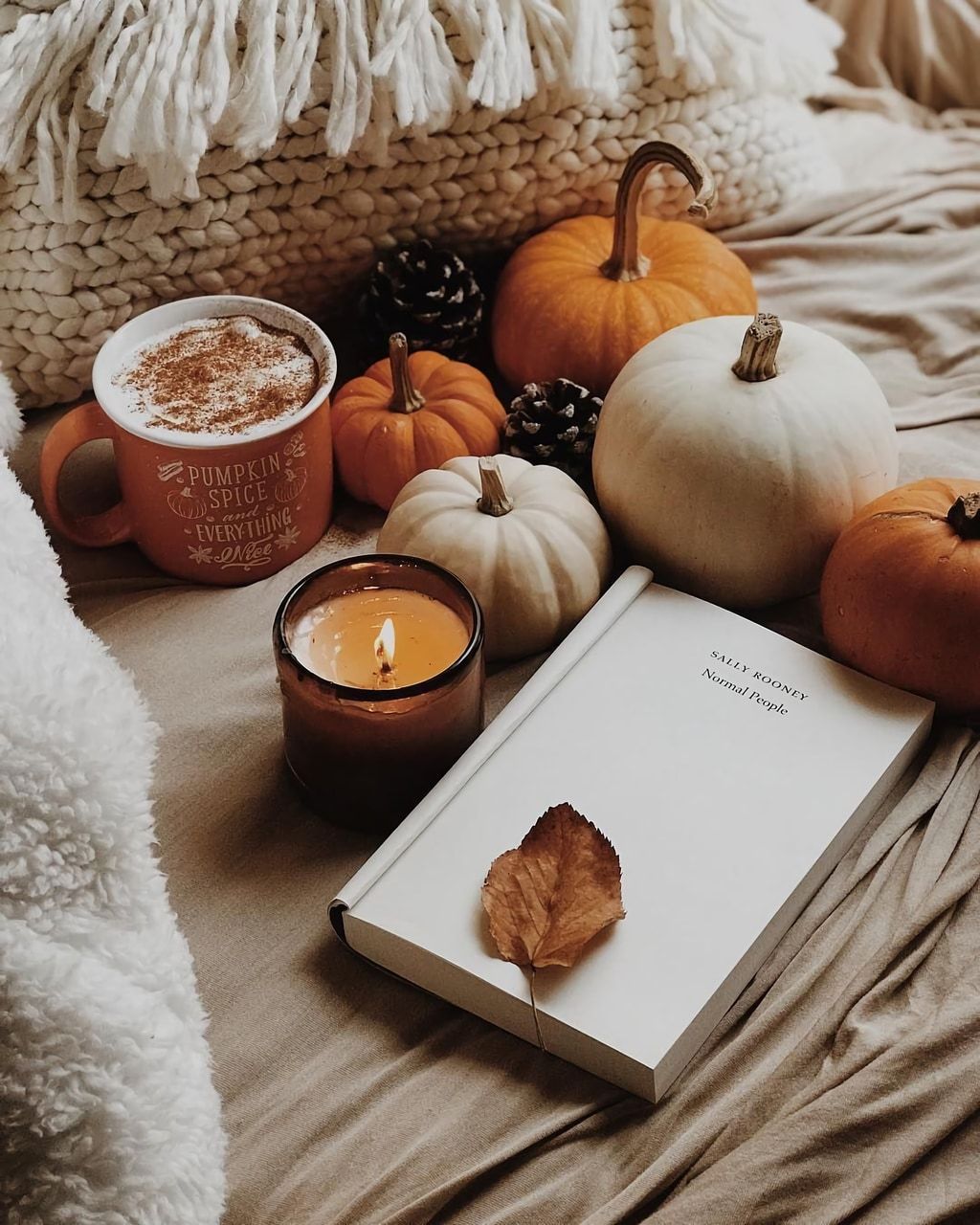 A book, candle and pumpkins on the bed - Cozy