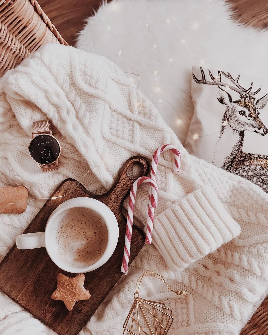 A cup of coffee on a wooden tray with a candy cane and a reindeer pillow. - Cozy