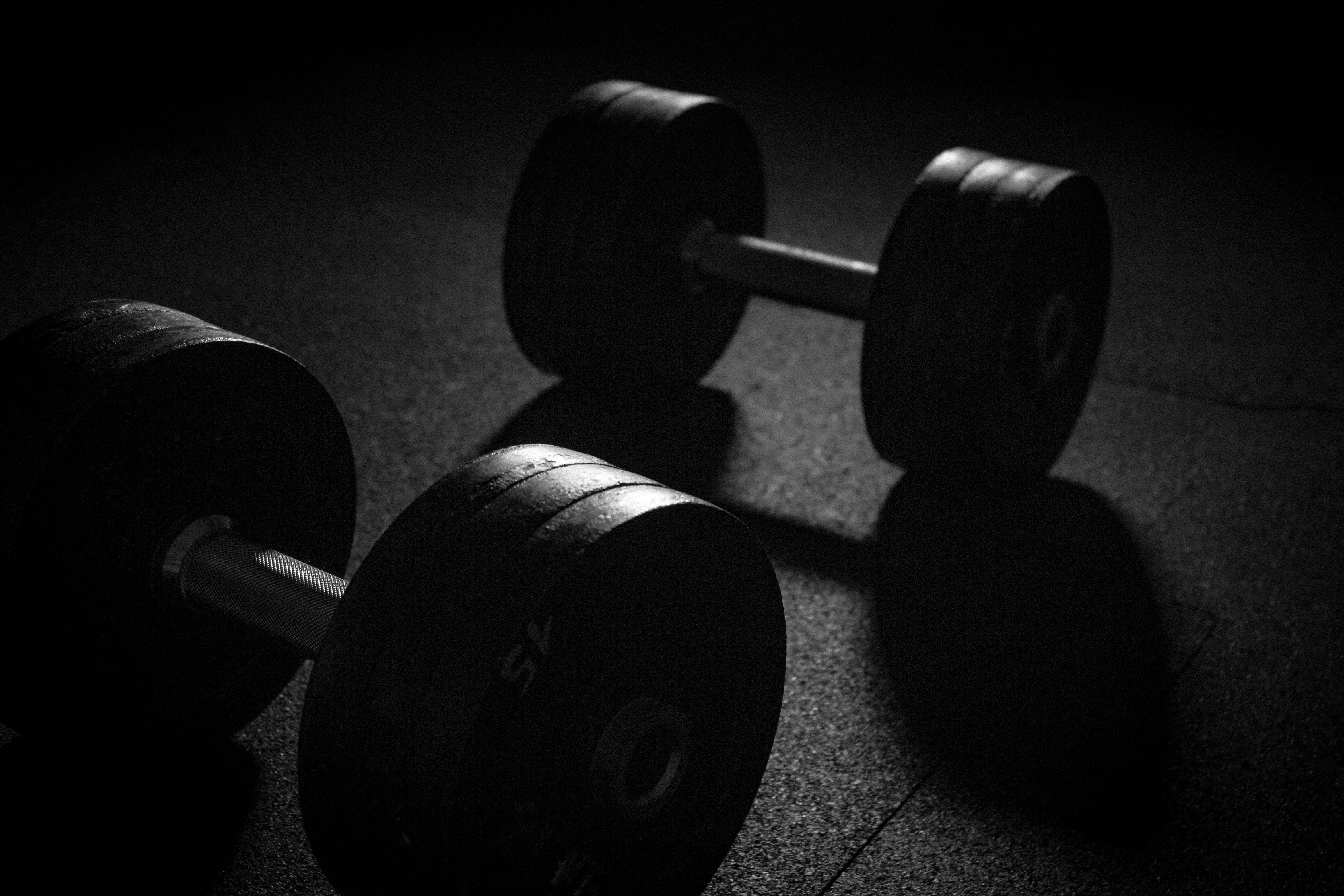 Two dumbbells sitting on a dark floor - Gym