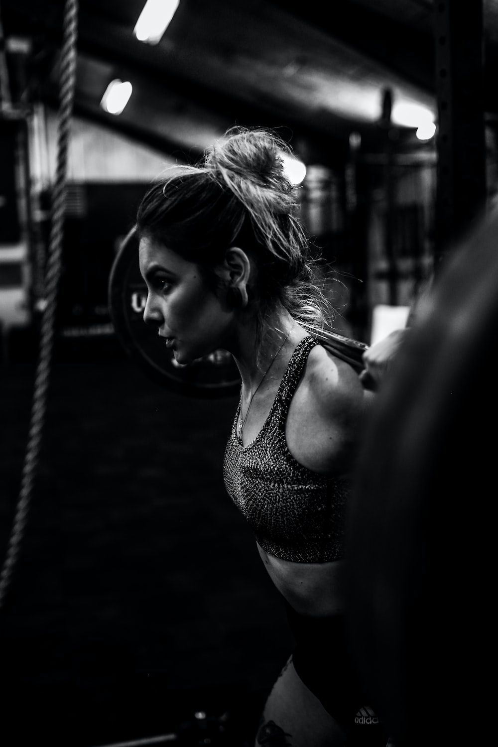 Grayscale photo of woman lifting a barbell - Gym