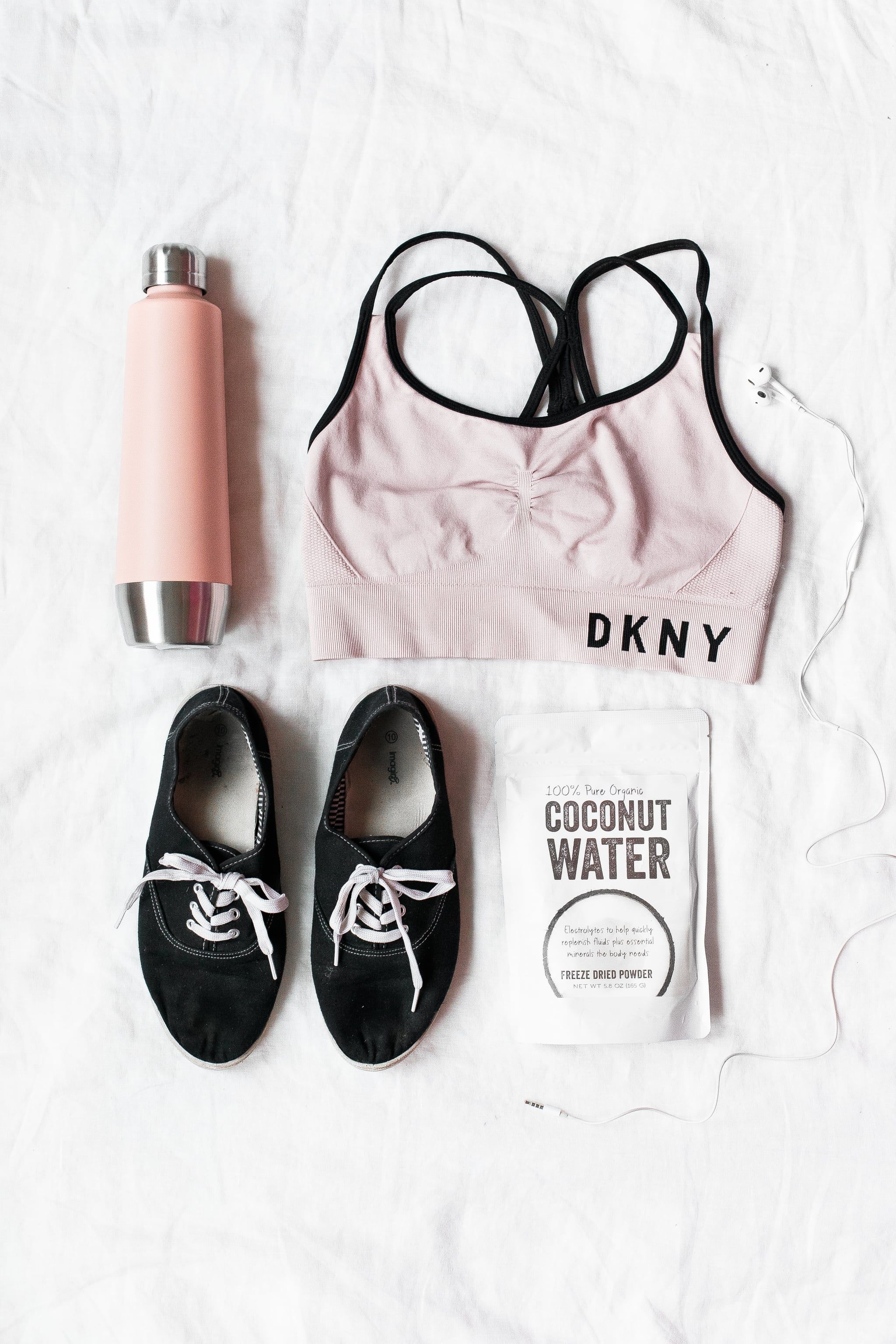 A pink DKNY sports bra, a water bottle, a bag of coconut water, and a pair of black sneakers - Gym