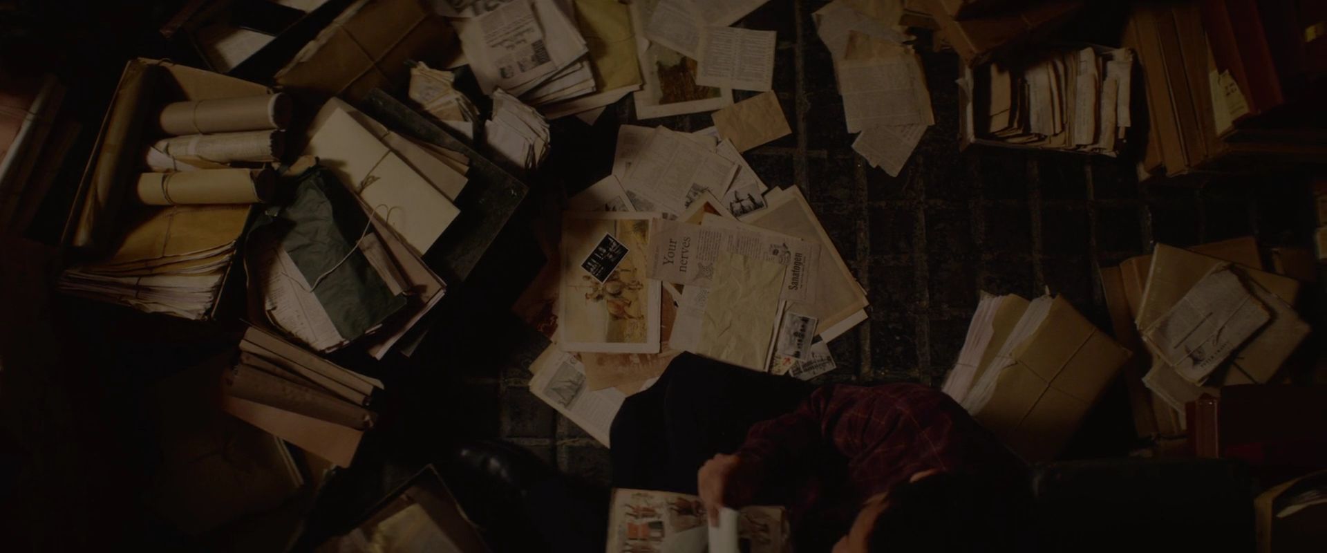 A person sitting on the floor surrounded by papers - Dark academia