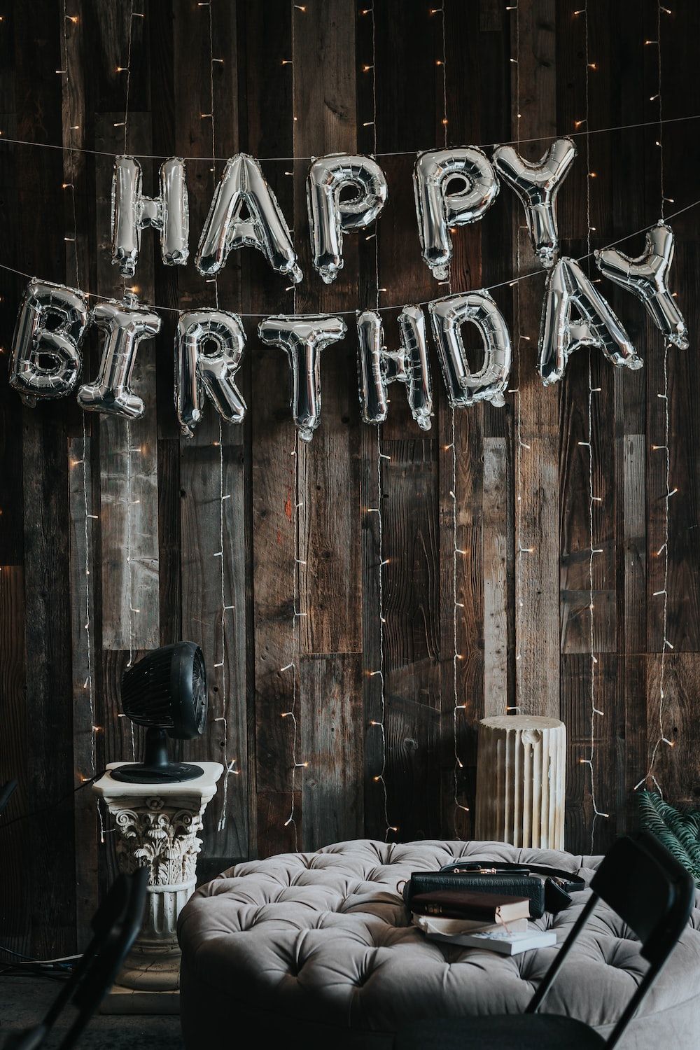 A room with a wooden wall and a sofa with a birthday banner above it. - Birthday