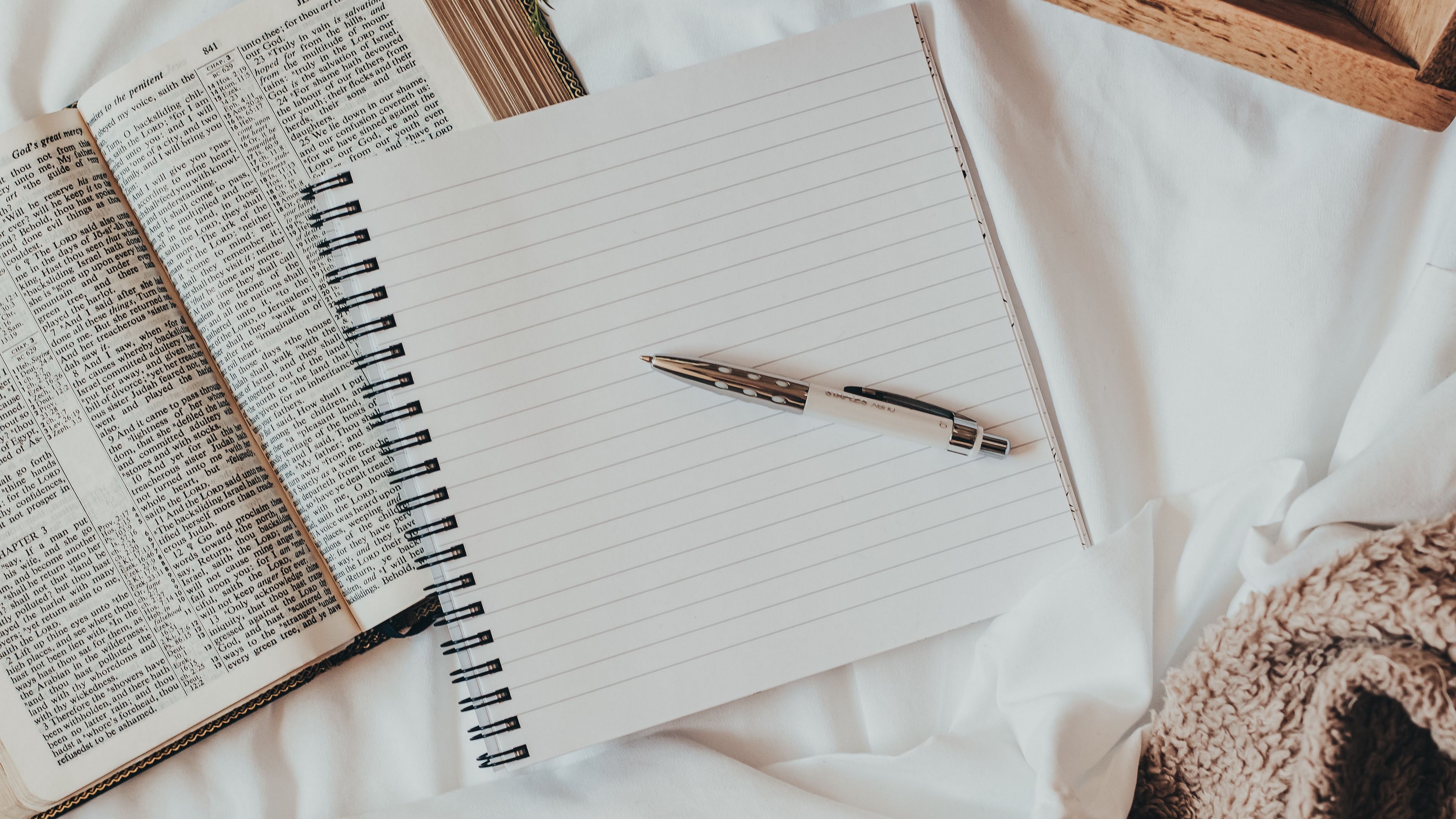 A notebook and pen next to an open bible - Study