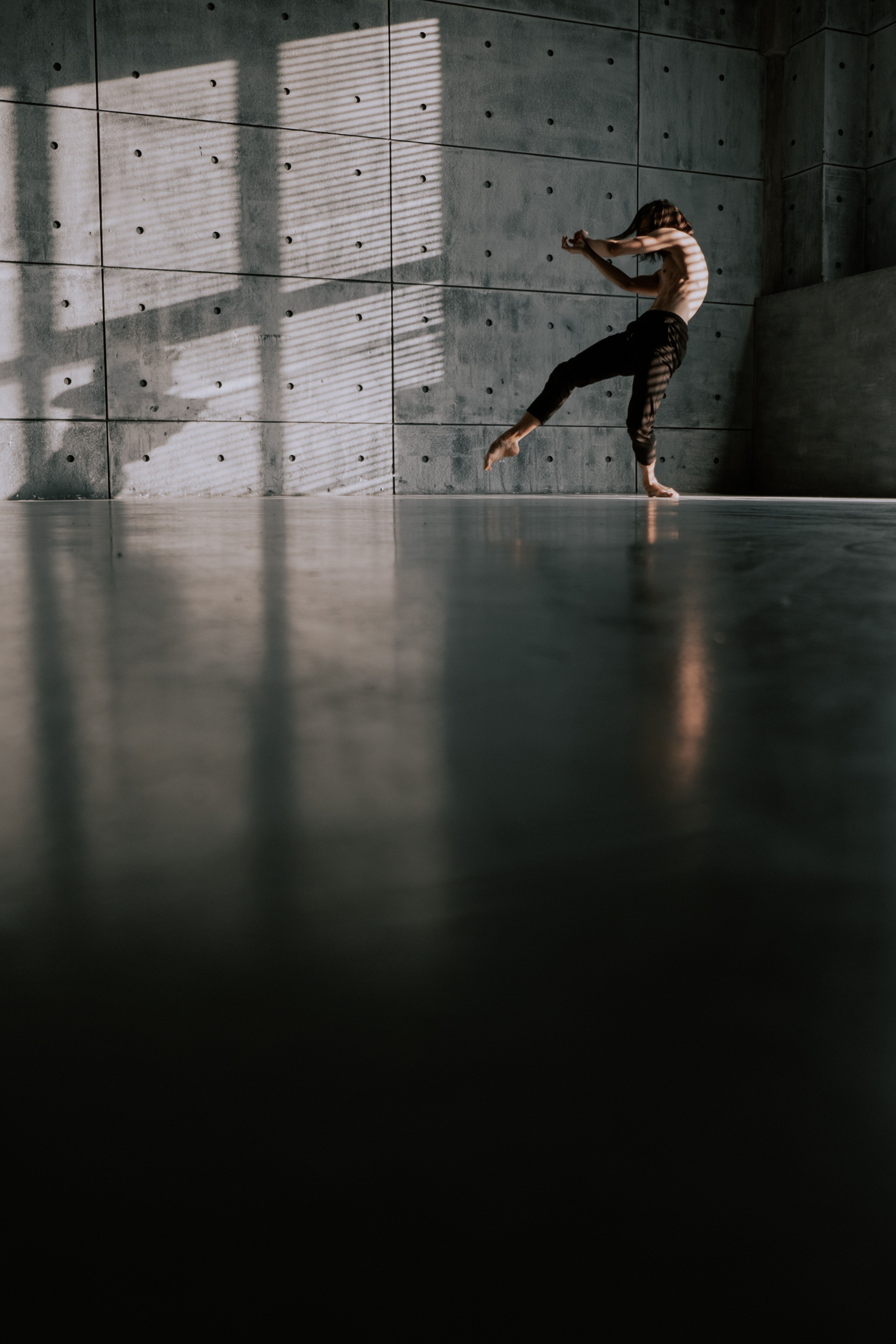 A woman dances in a concrete room with sunlight streaming in. - Dance, ballet