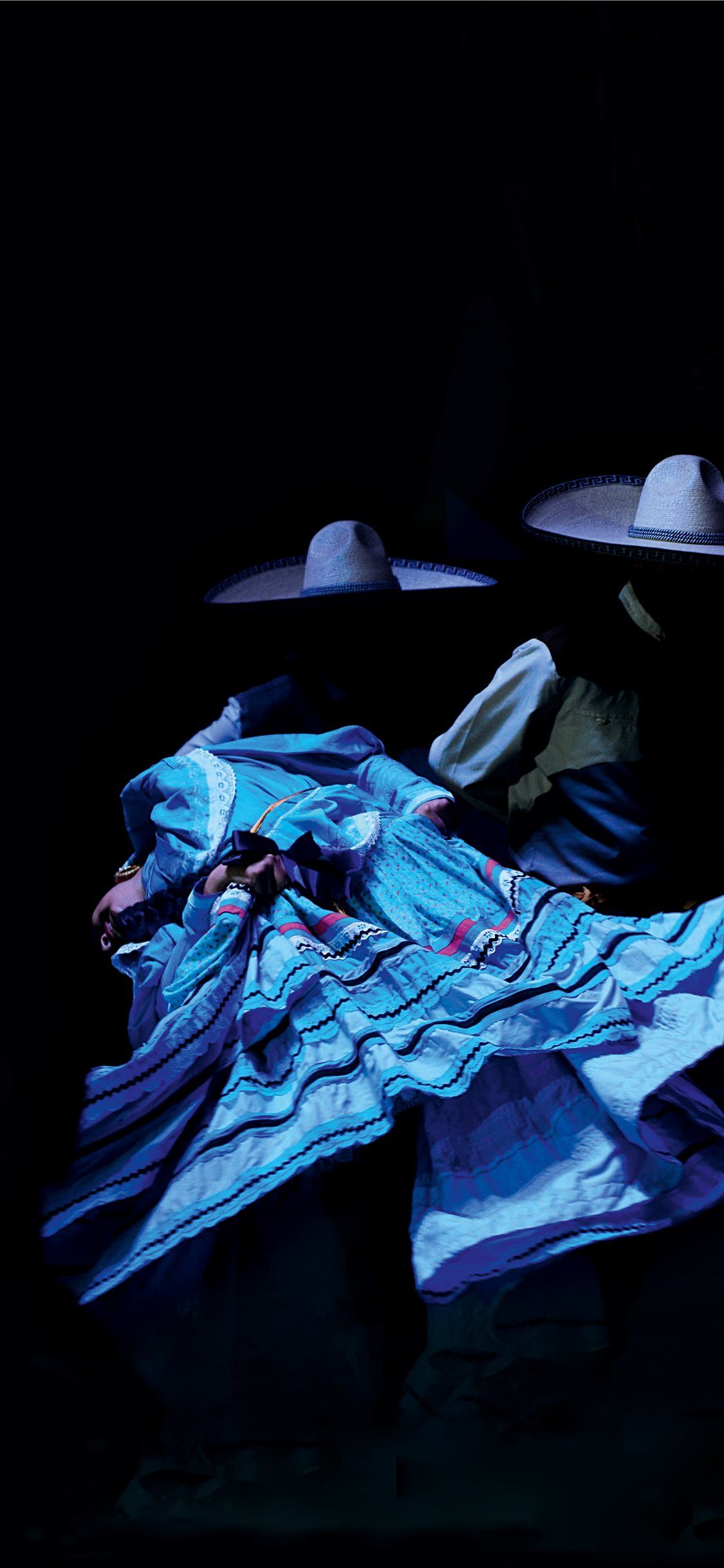 A man and a woman in sombreros dance together in a dark room. - Dance, Mexico