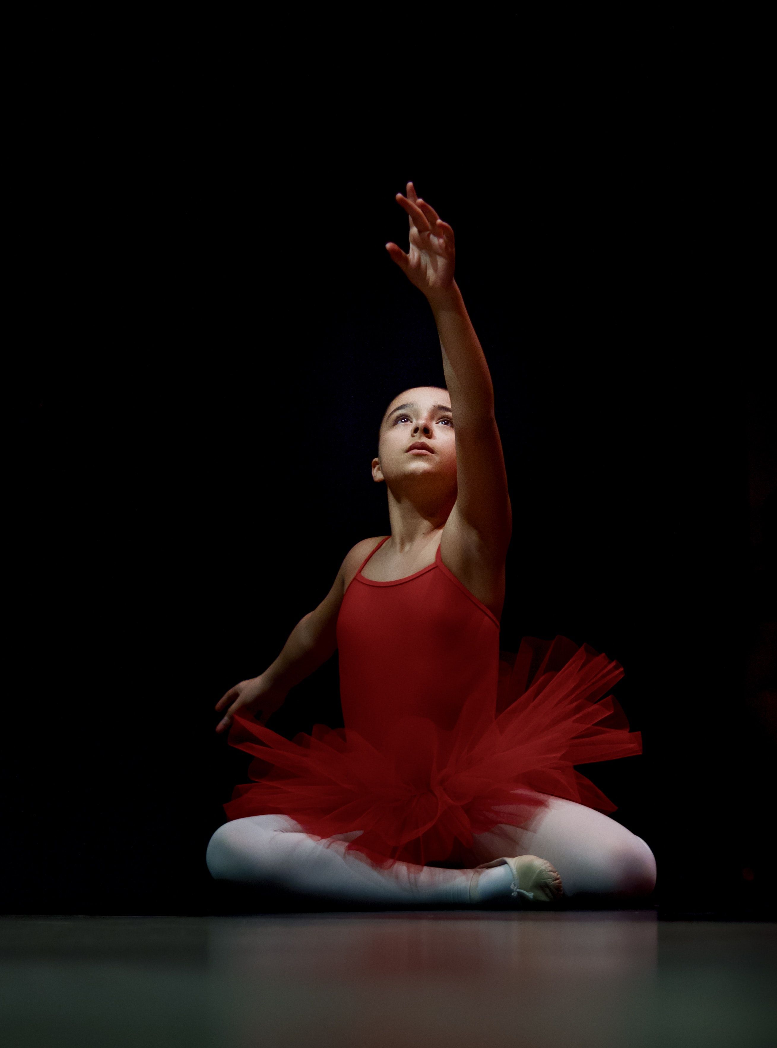 A young ballerina in a red tutu sitting on the floor - Dance, ballet