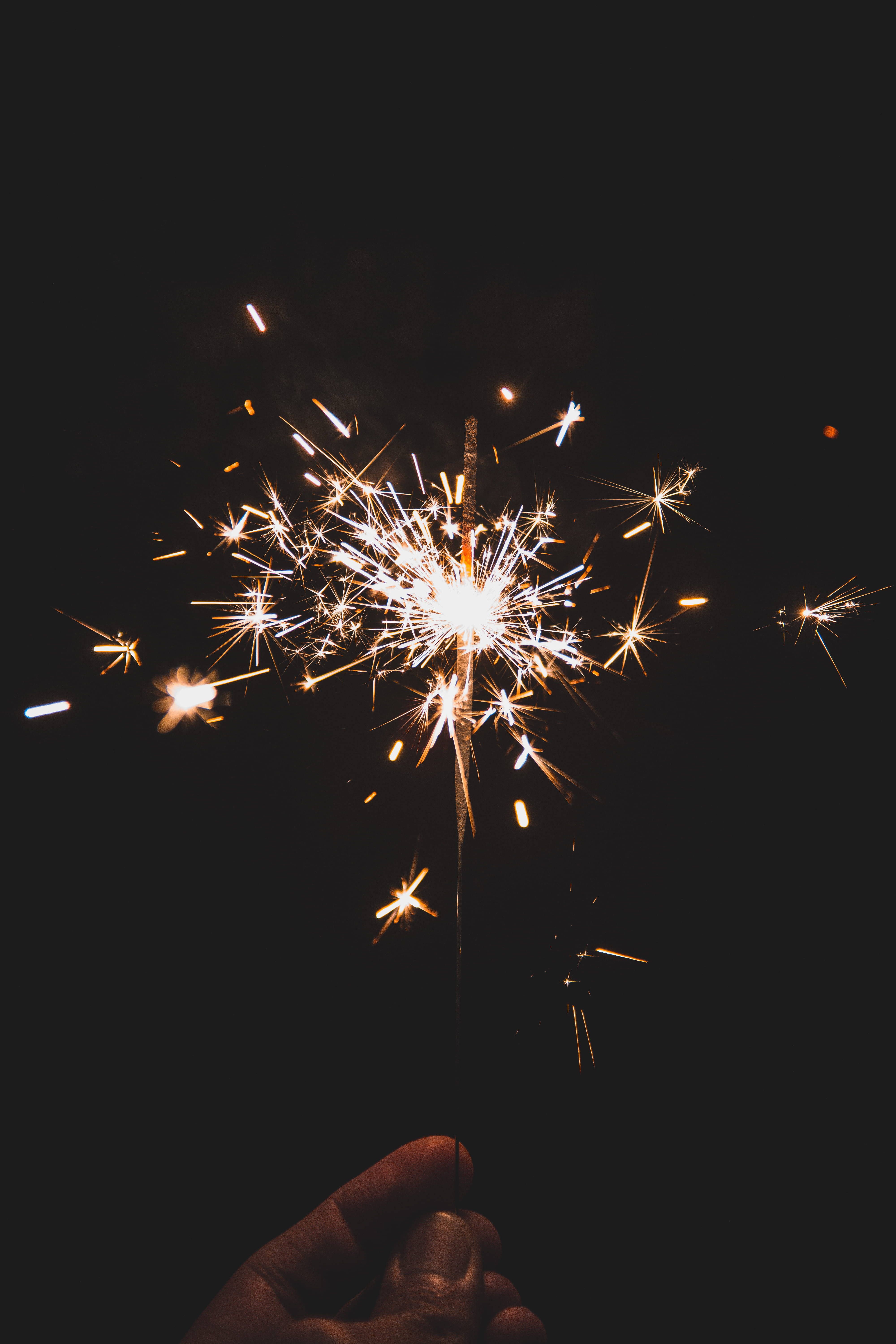 A person holding up sparklers in the dark - New Year