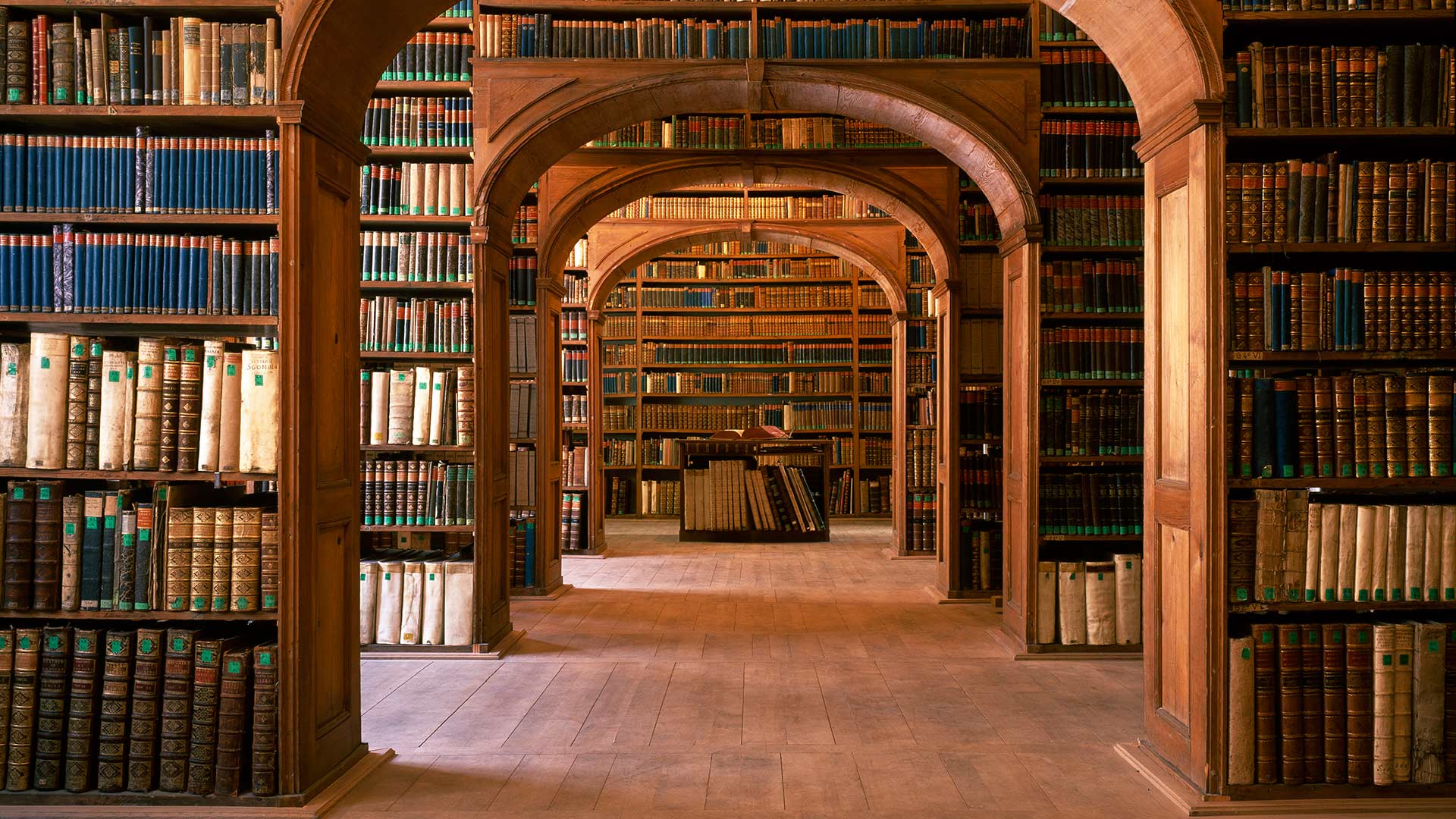 A long hallway with many bookshelves and books - Library