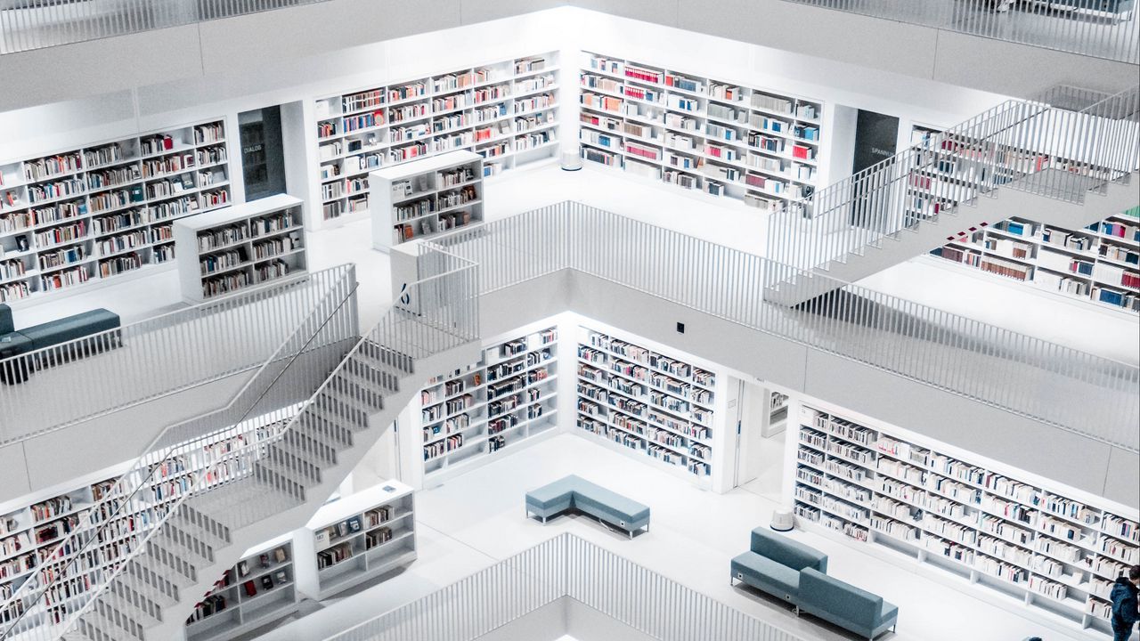 A white library with books on the shelves and blue couches. - Library