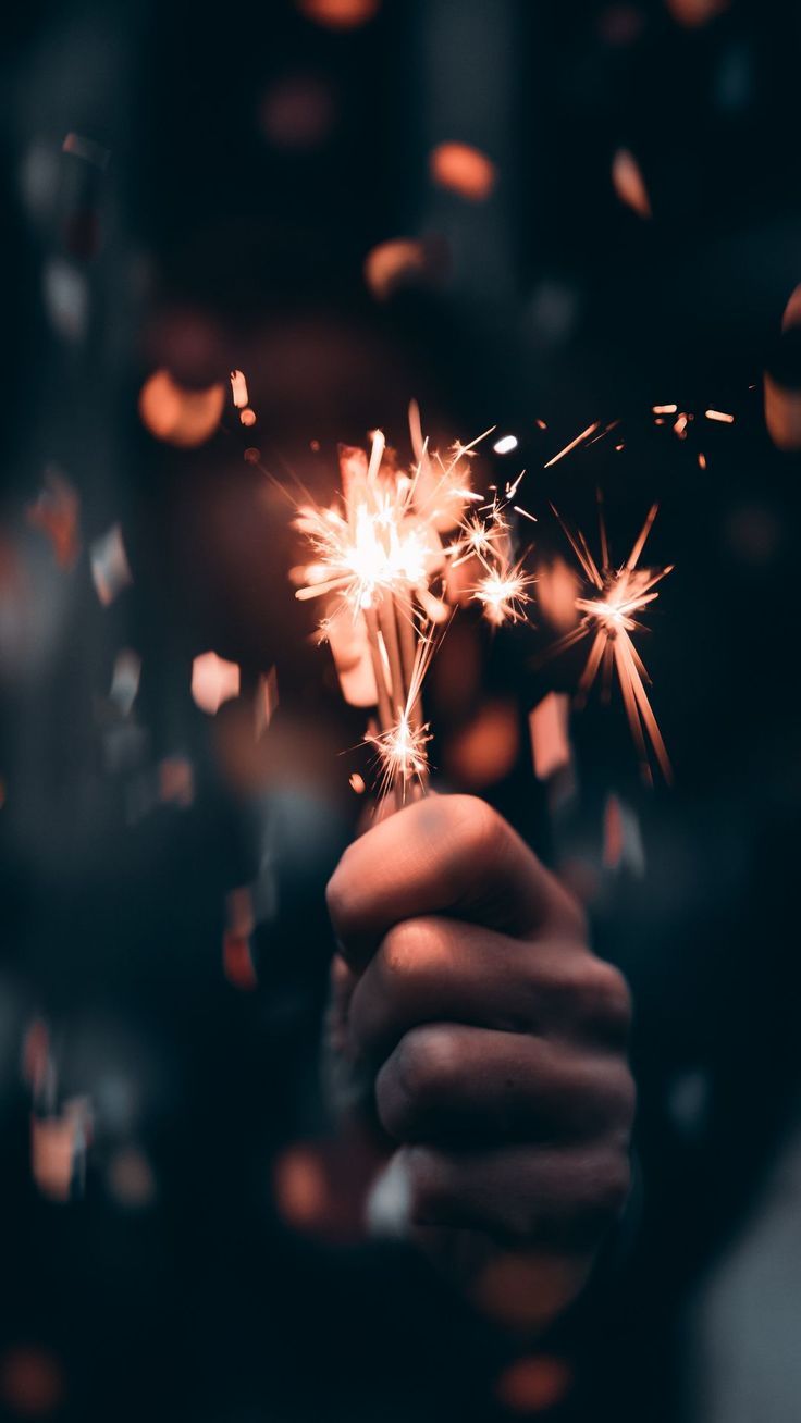 A person holding a sparkler in their hand. - New Year