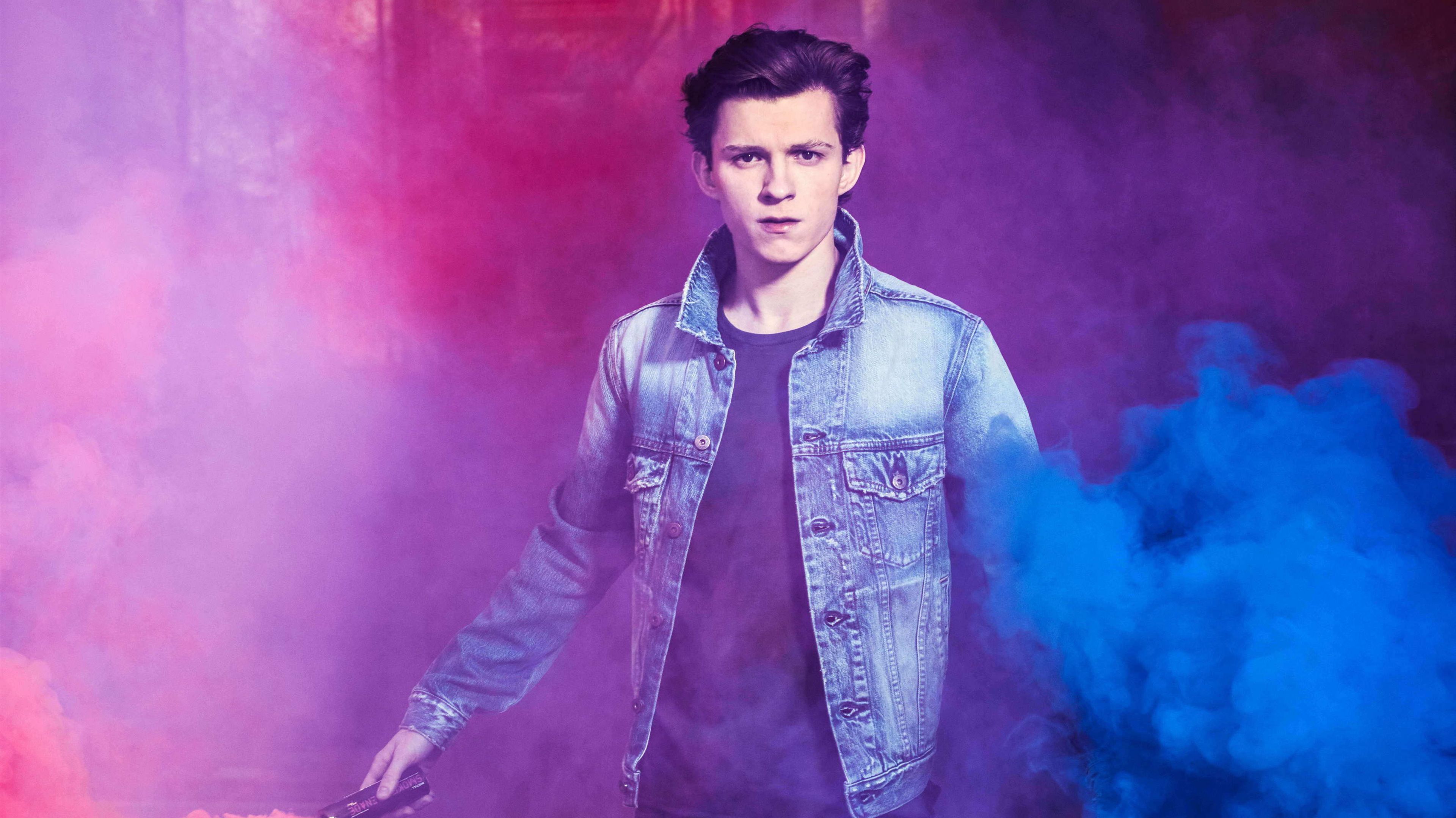 A young man in blue jeans and jacket standing on top of purple smoke - Tom Holland