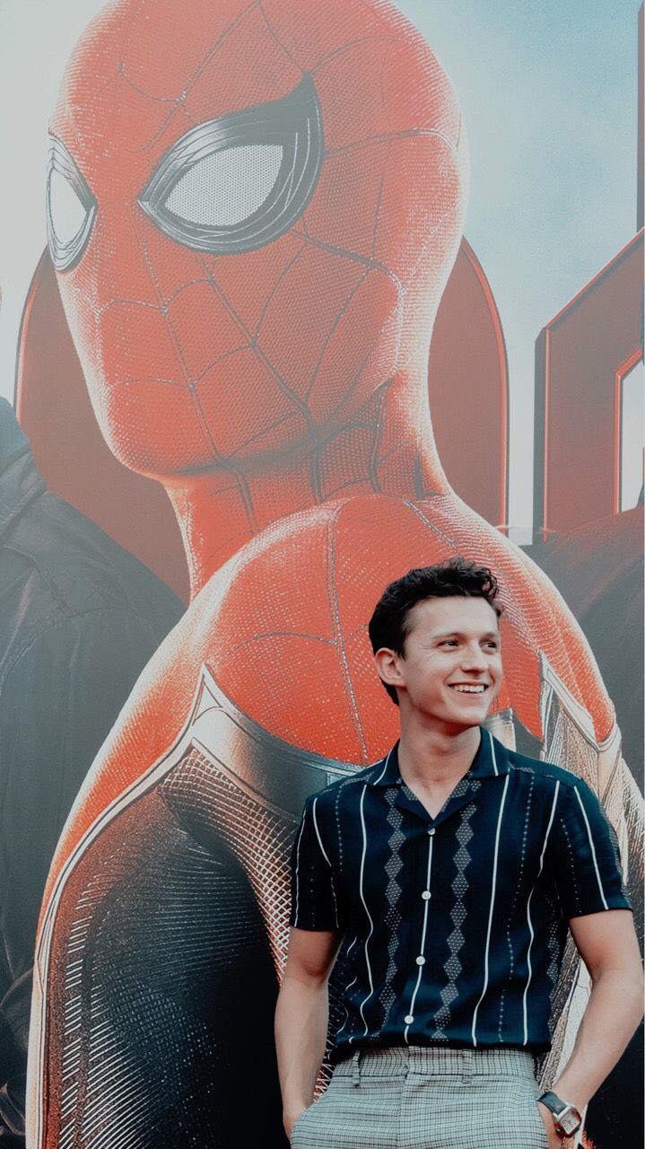 Tom Holland standing in front of a Spiderman poster - Tom Holland