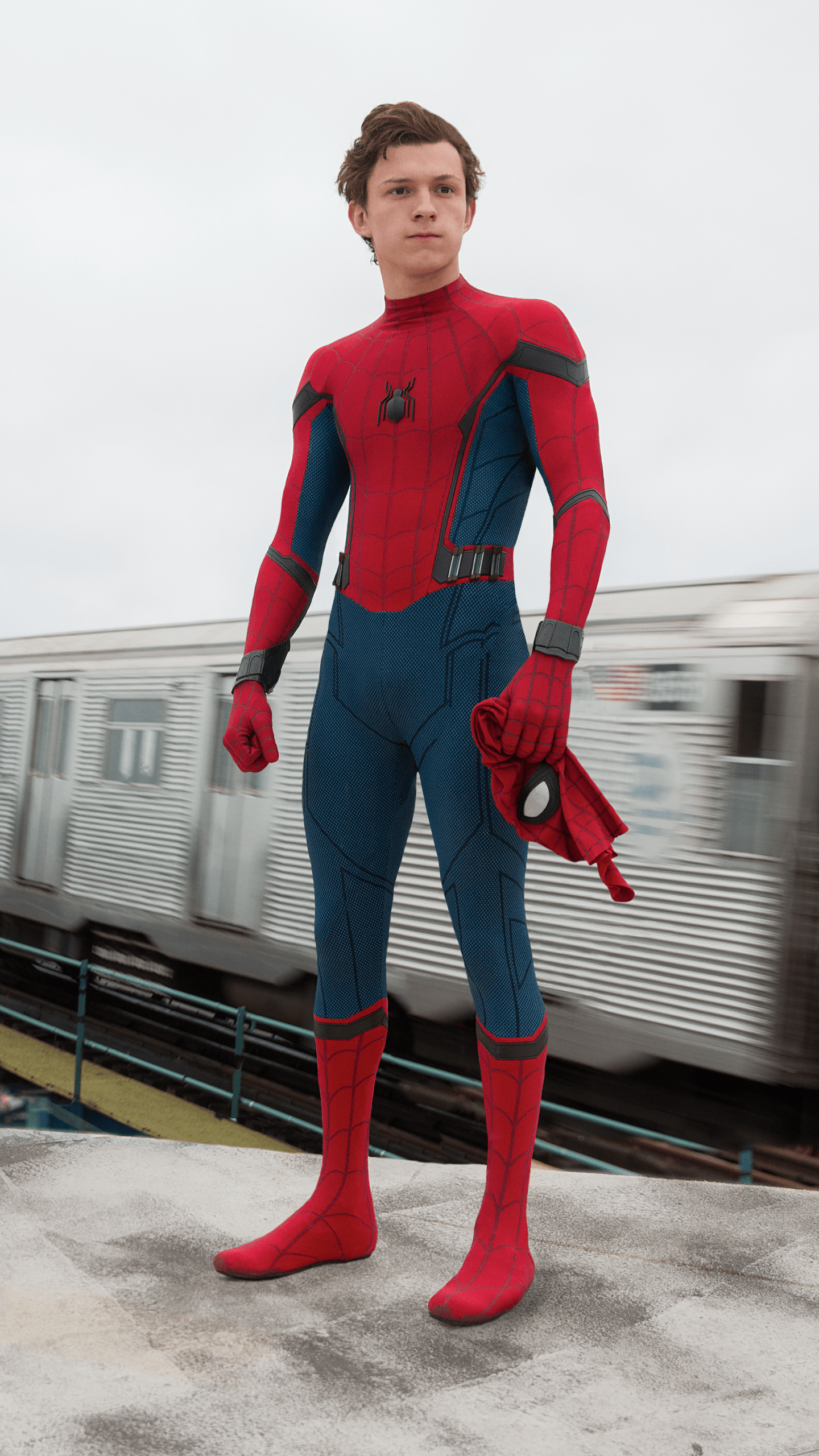 A man in spiderman costume standing on the sidewalk - Tom Holland