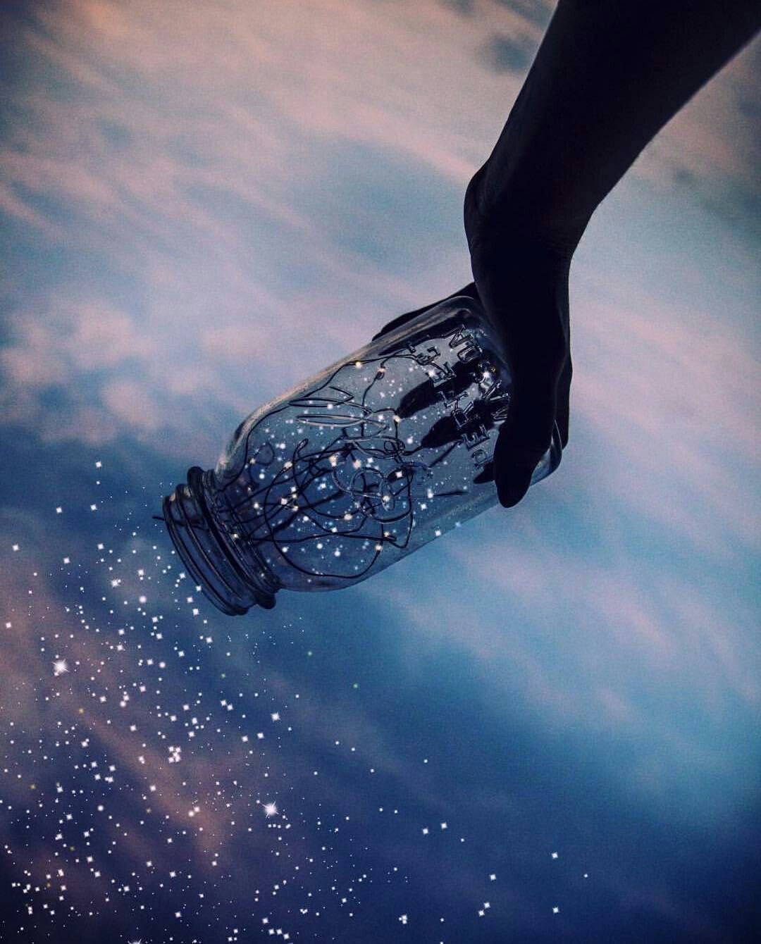 A hand holding a jar with a string of stars in it - Photography, indigo, magic