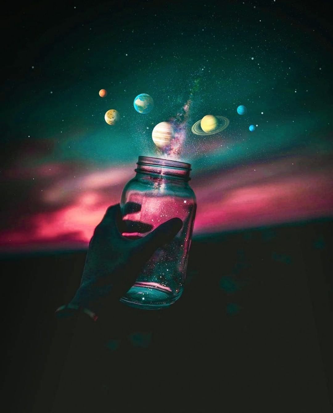 A hand holding up an empty jar with planets inside - Photography