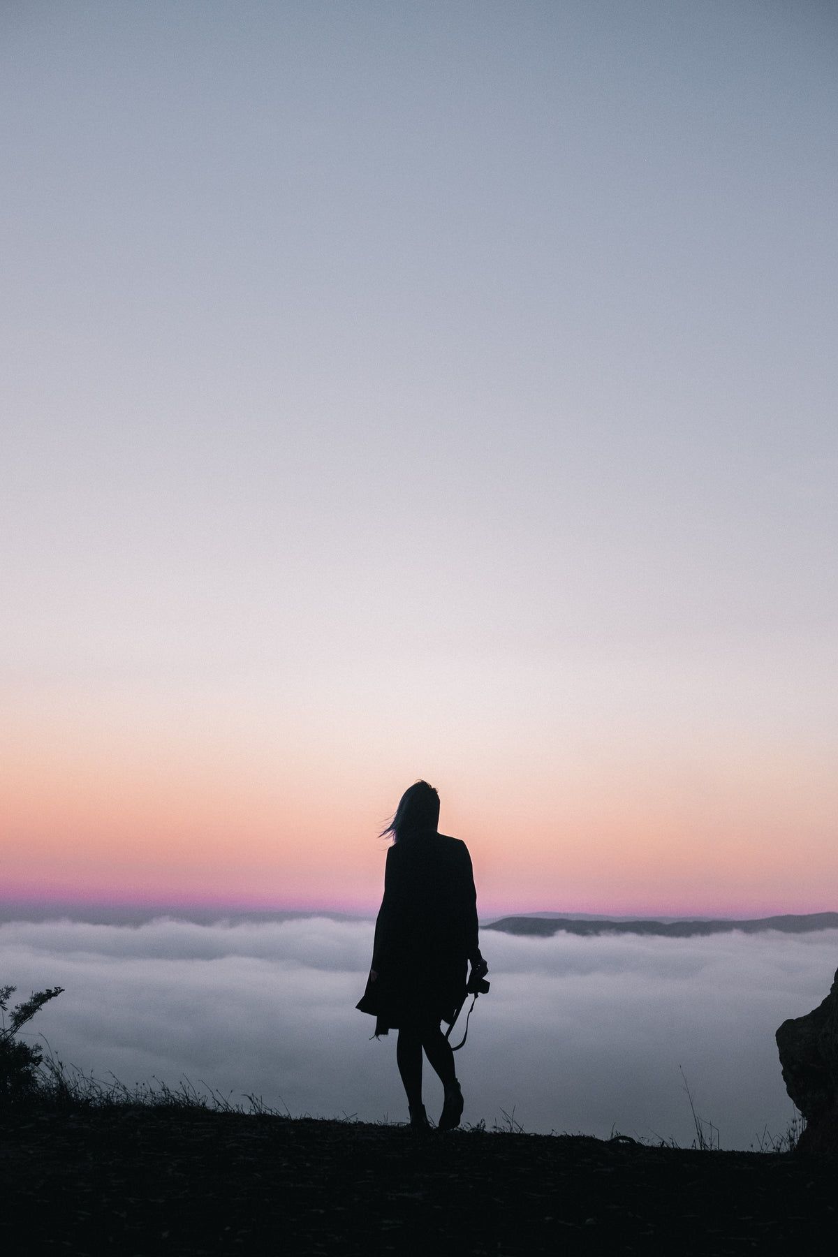 A woman standing on a hill with a sunset in the background - Photography