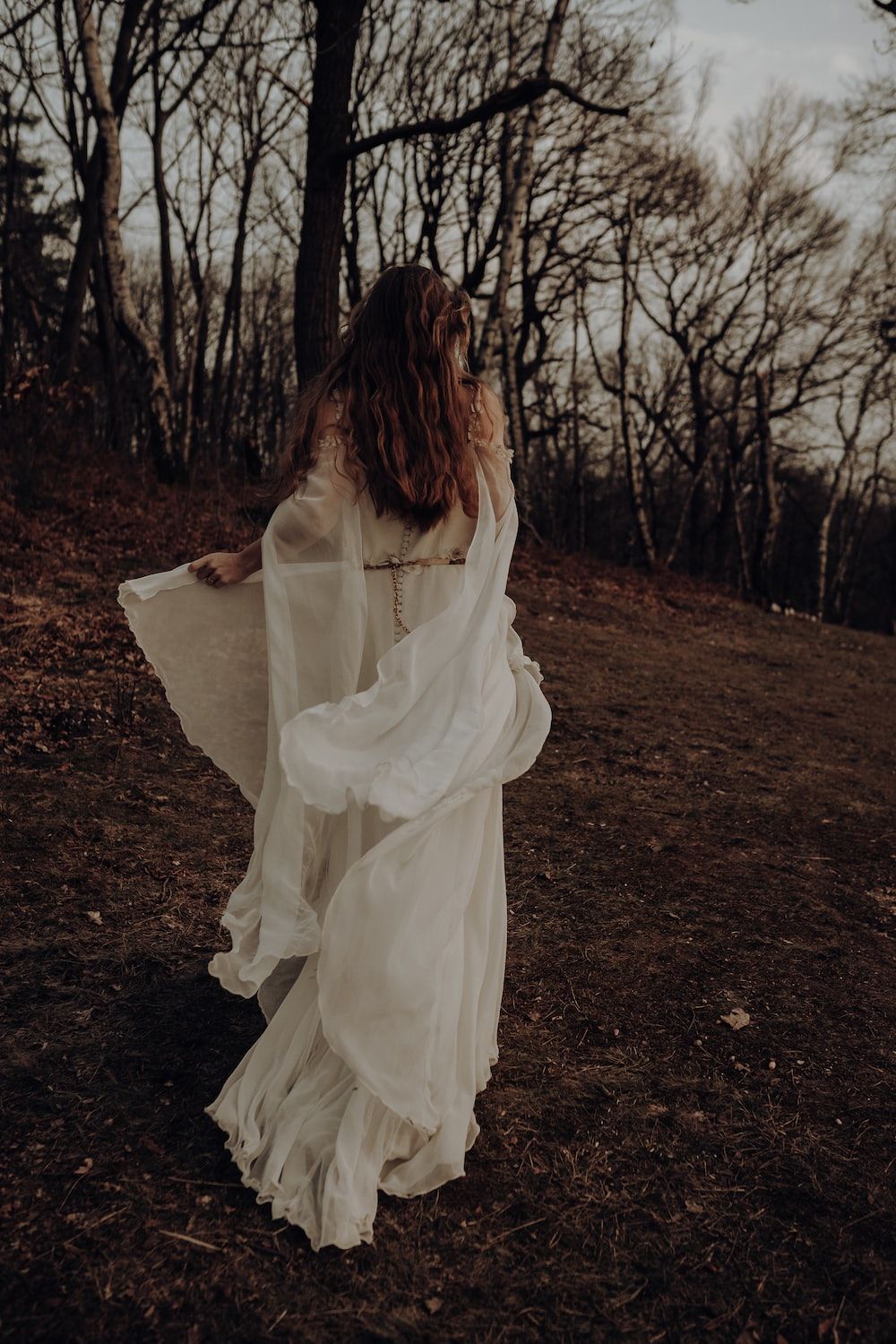 Bride in flowing white dress walking through the woods - Princess