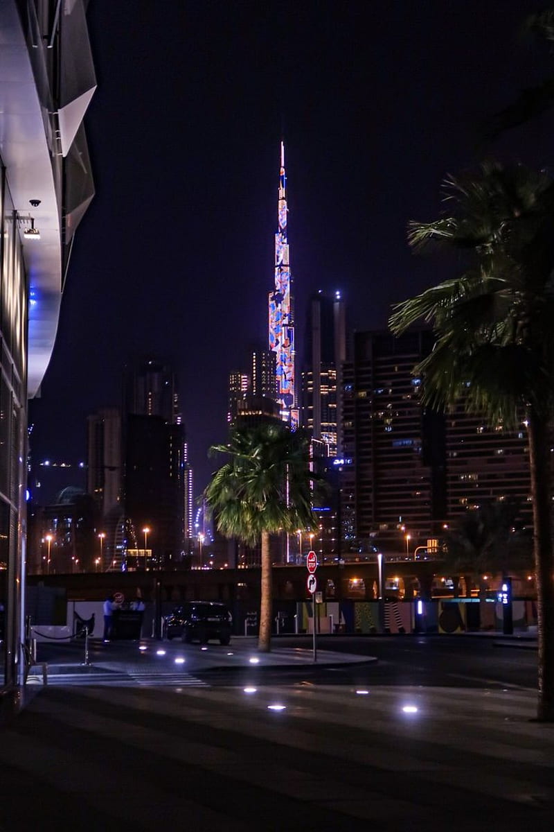 A night view of the Burj Khalifa in Dubai, lit up in a rainbow of colors. - City, Dubai