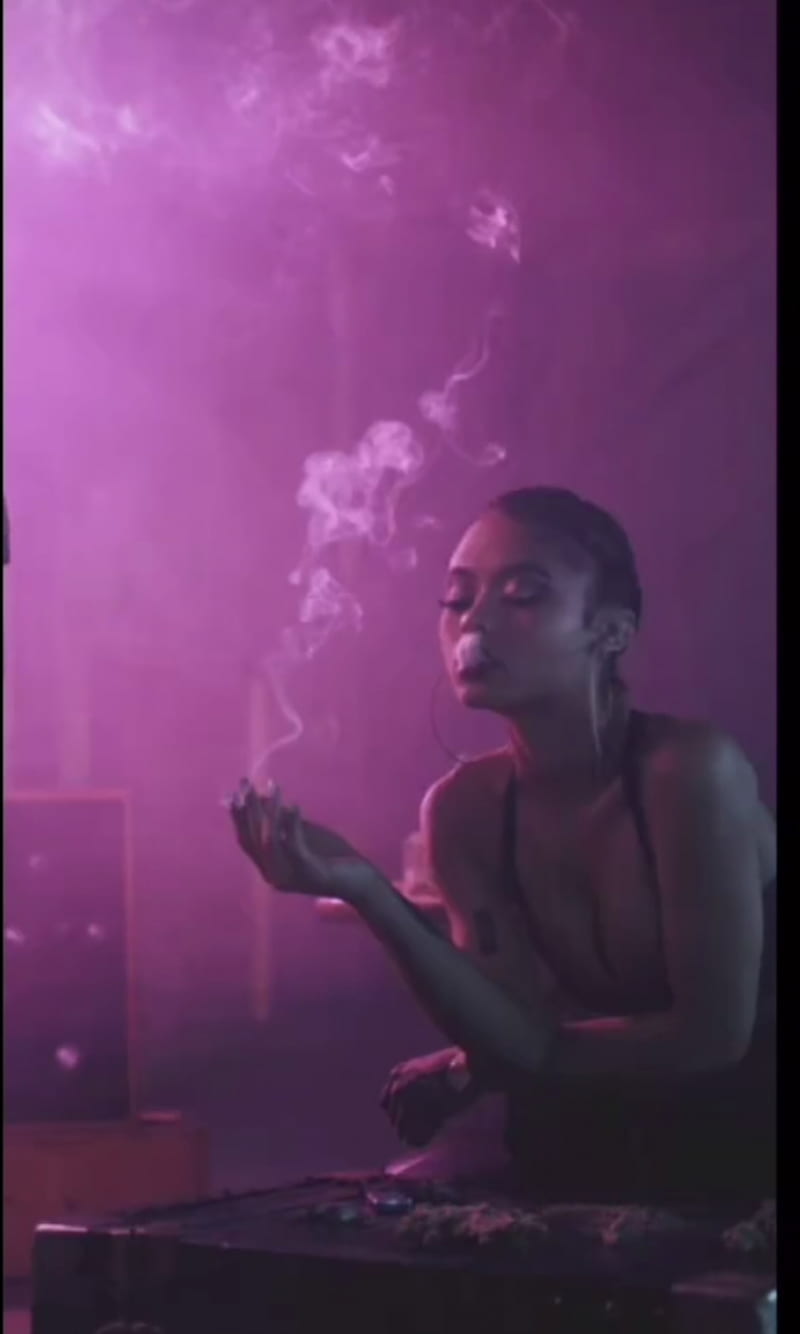 A woman blowing smoke from her mouth in a purple room - Smoke