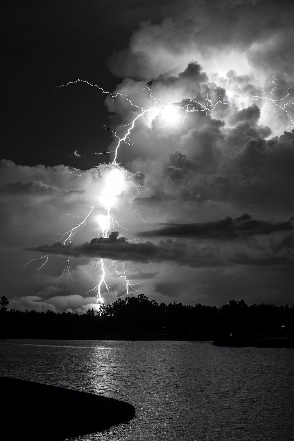 grayscale photo of lightning over body of water photo