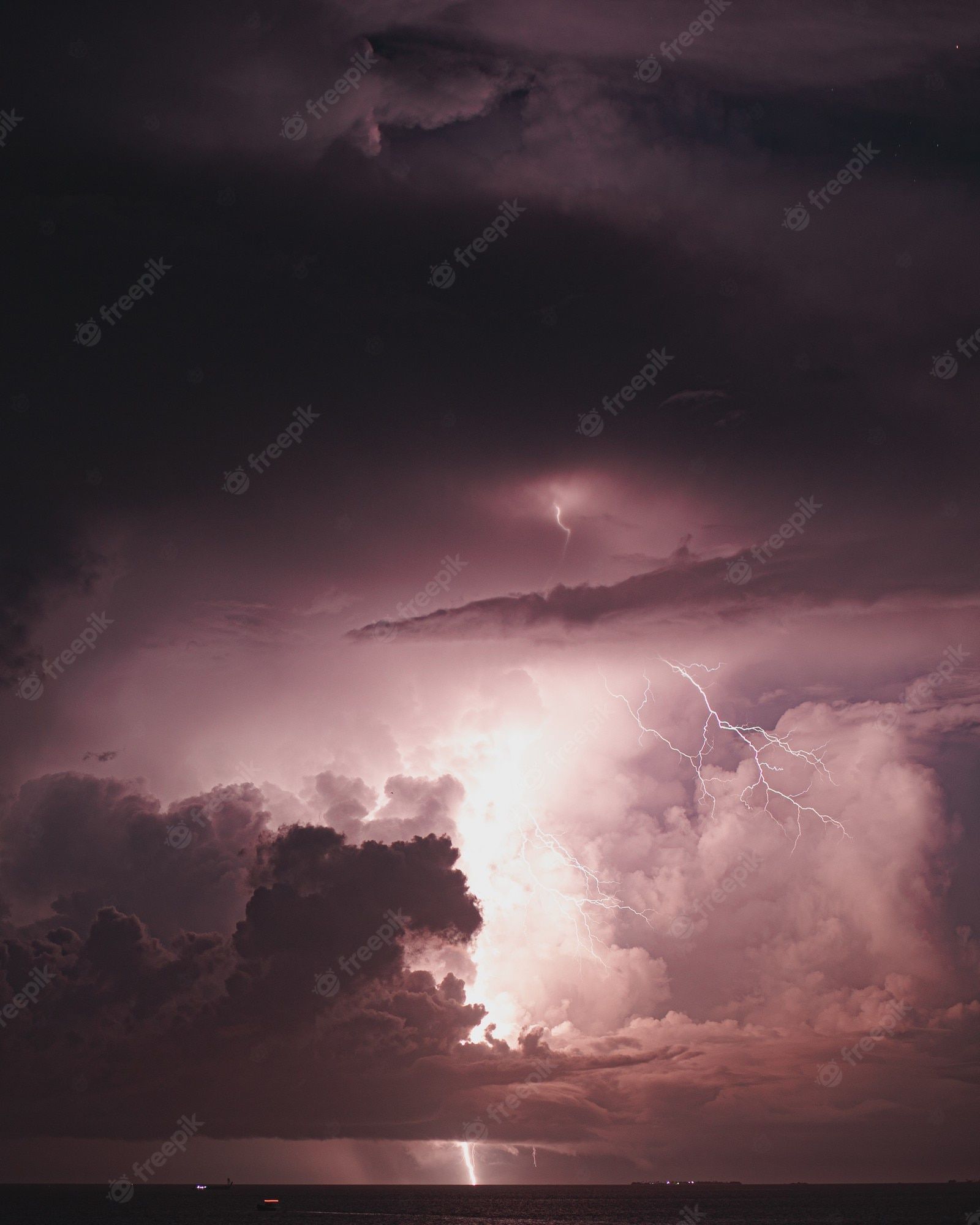Lightning striking through the clouds over the ocean - Lightning