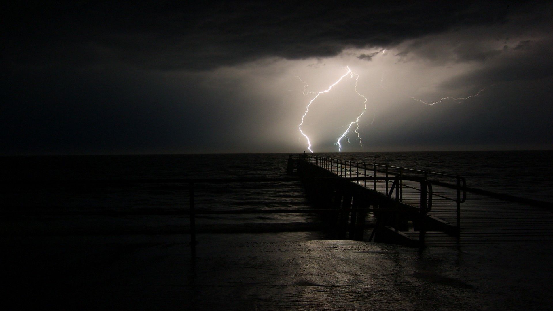 A lightning bolt strikes the water near some piers - Lightning