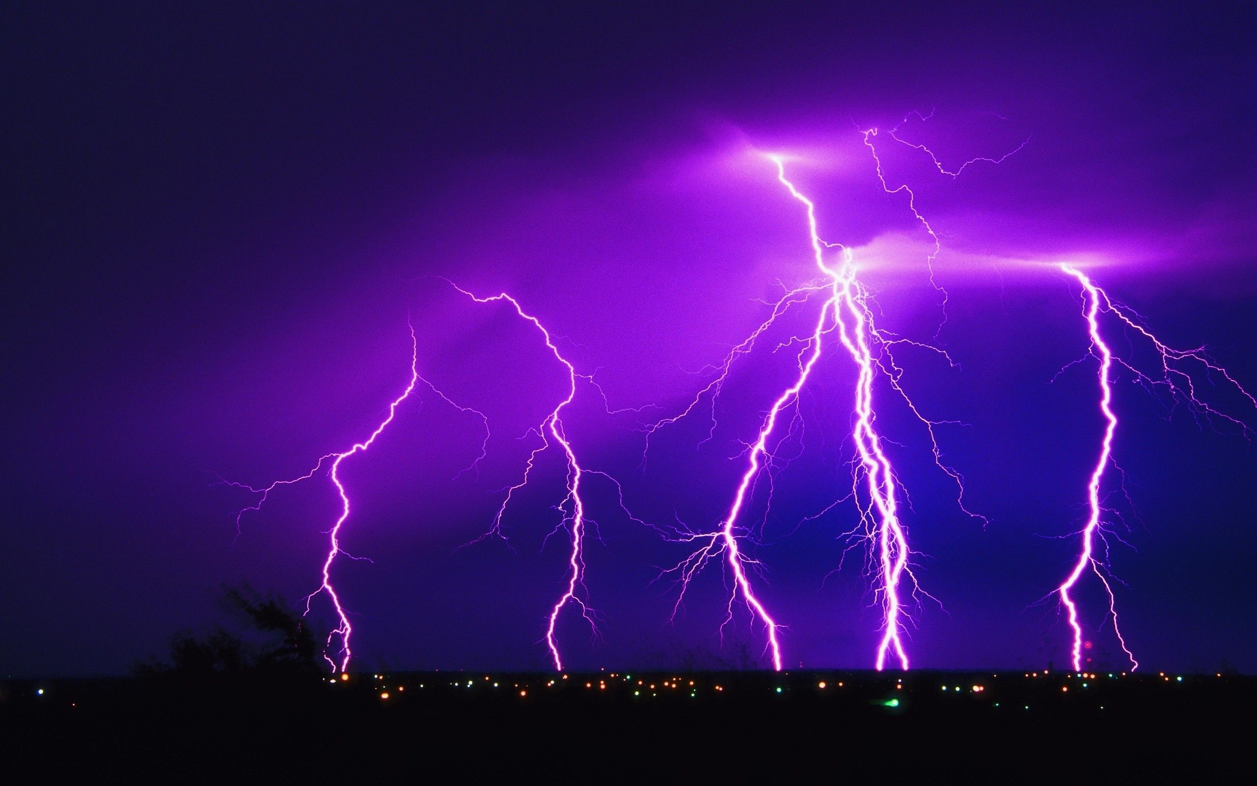 A purple lightning storm over a city at night. - Lightning