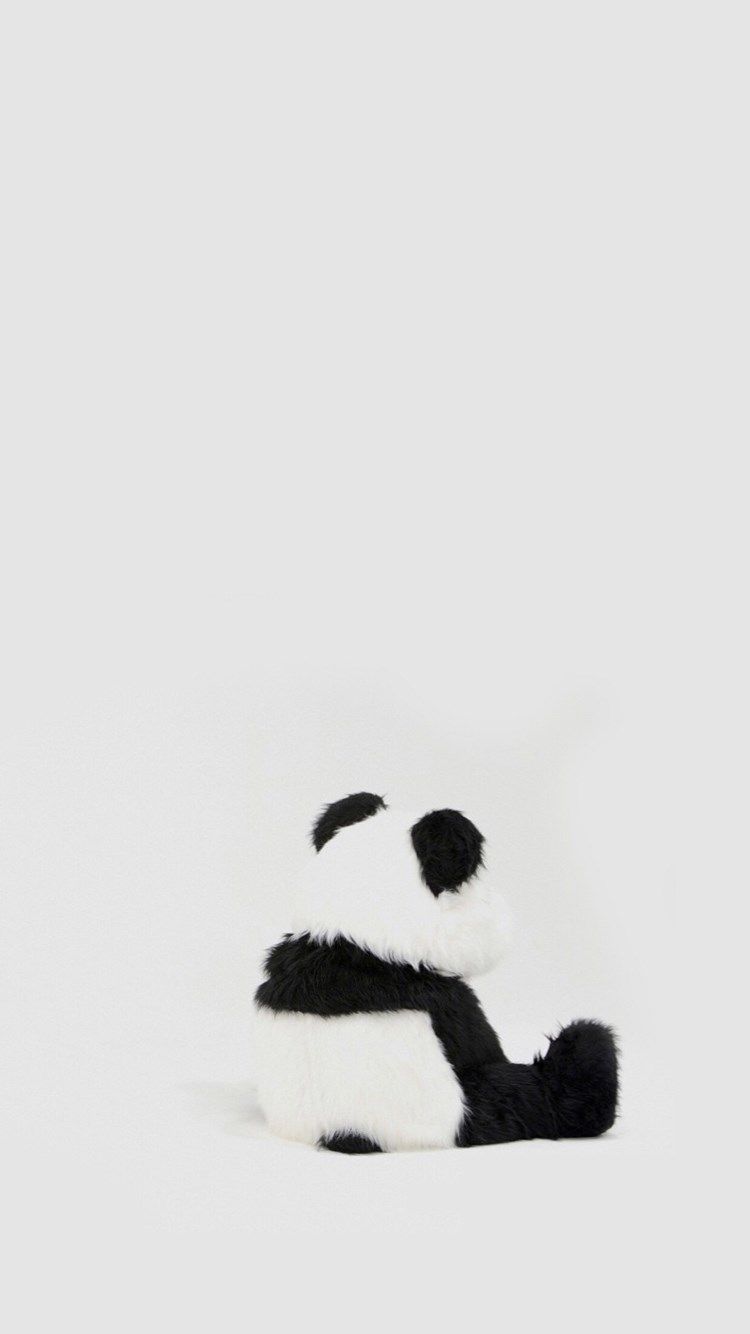 A stuffed panda bear toy sitting on a white surface - Panda