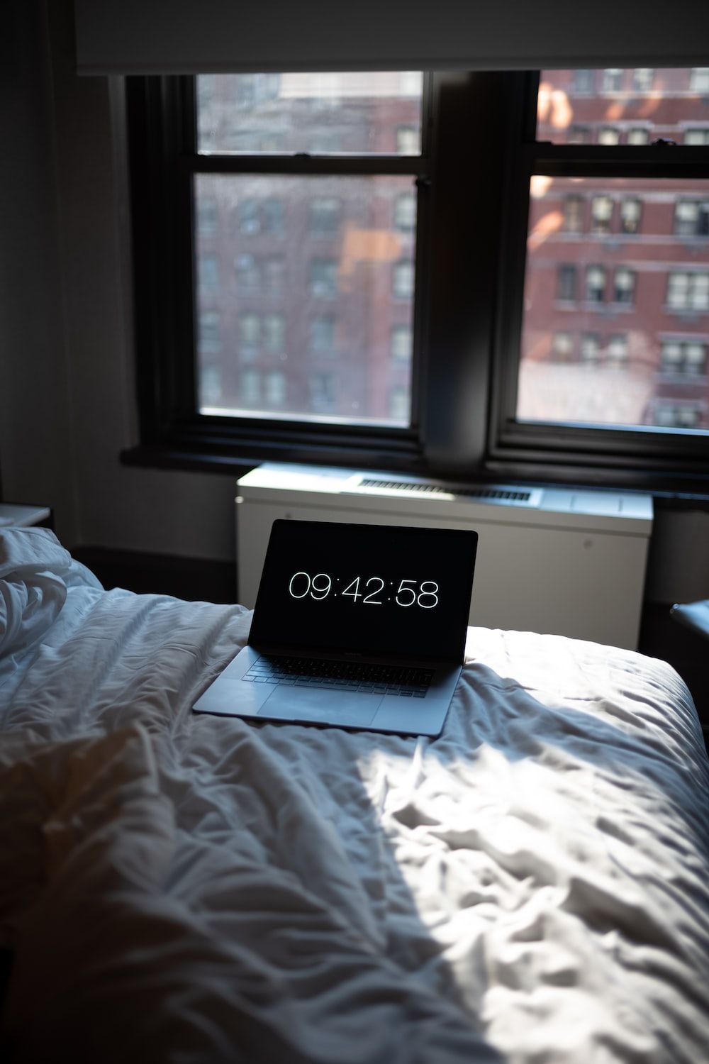 A laptop on a bed with the time showing 9:42:58 - School