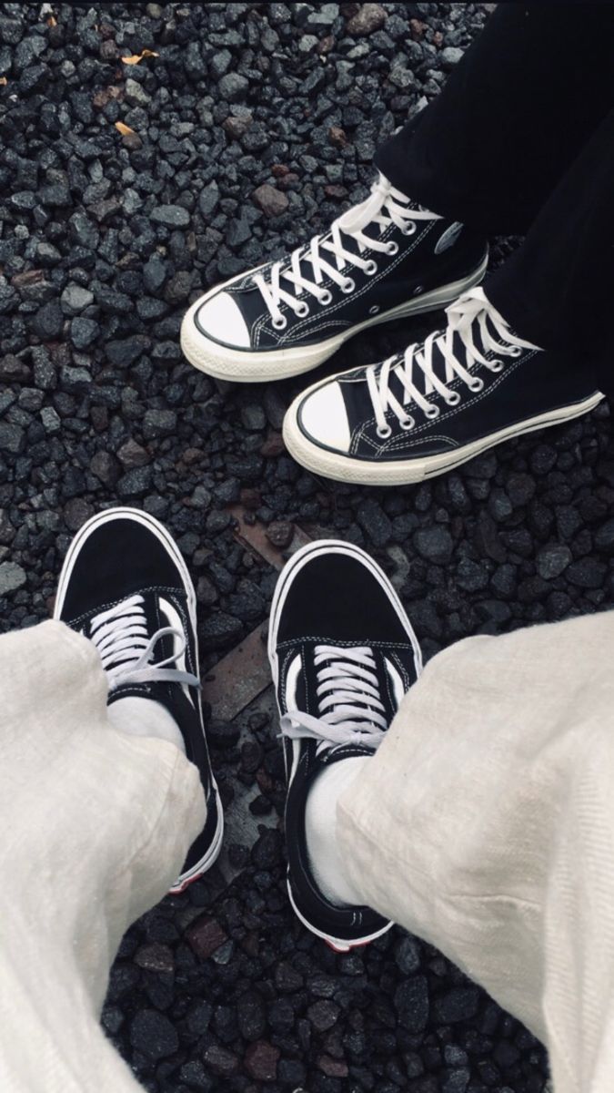 An image of black and white converse worn by two people. - Converse