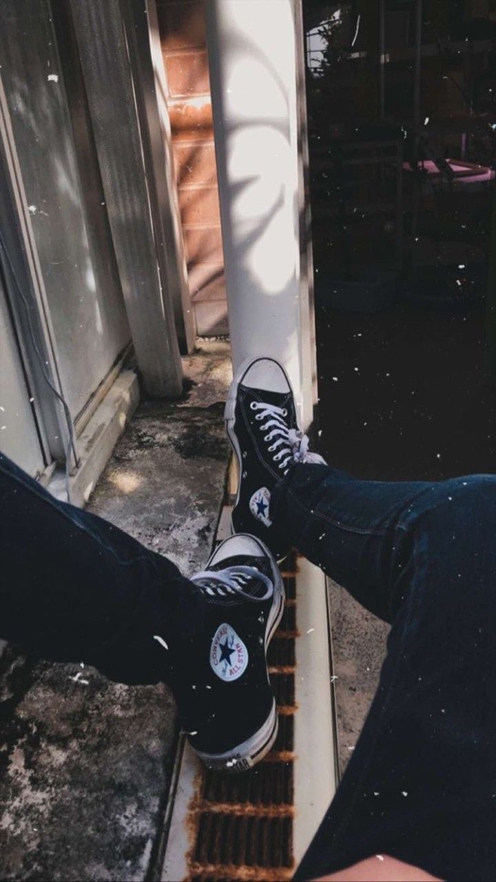 A person sitting on the edge of something - Converse