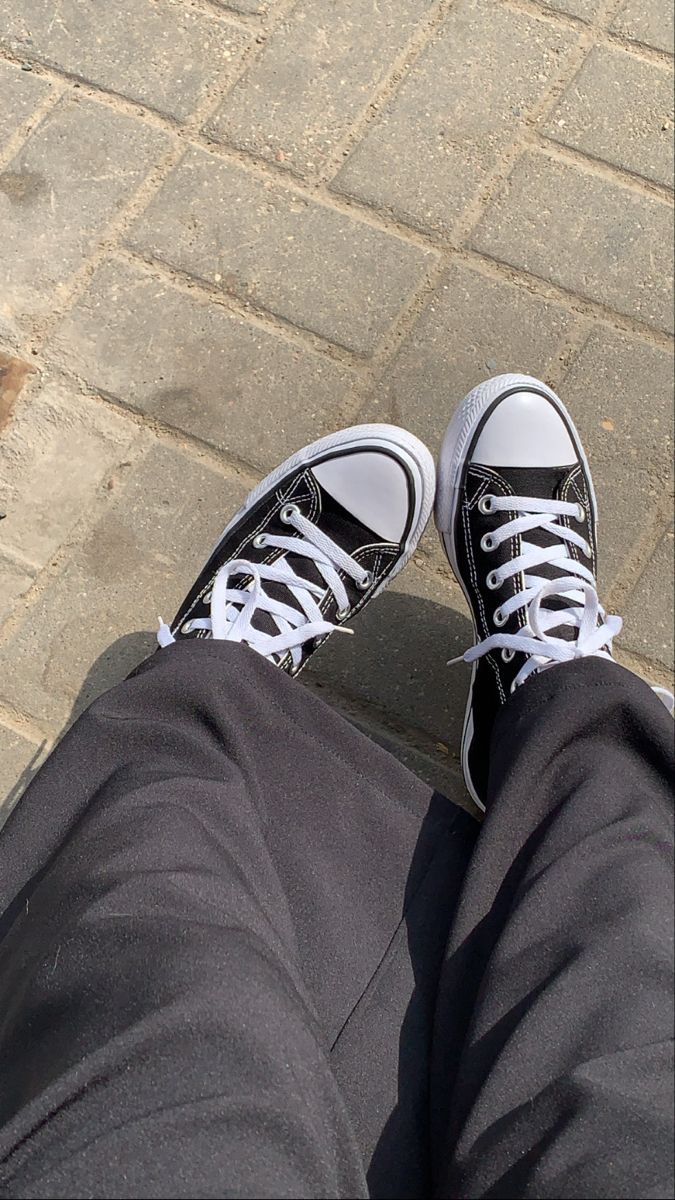 A person wearing black and white converse sneakers. - Converse