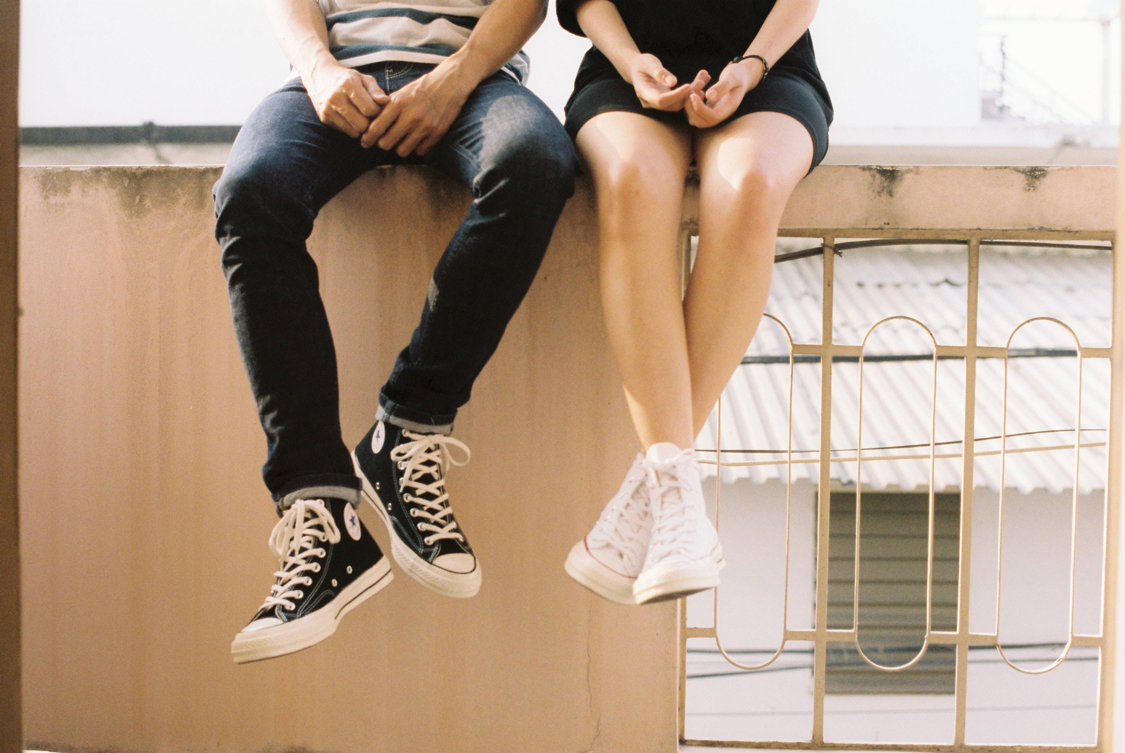 A man and a woman sitting on a ledge - Converse