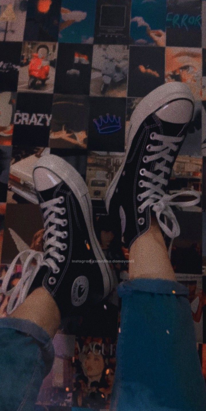 A person wearing black and white sneakers on top of some tiles - Converse