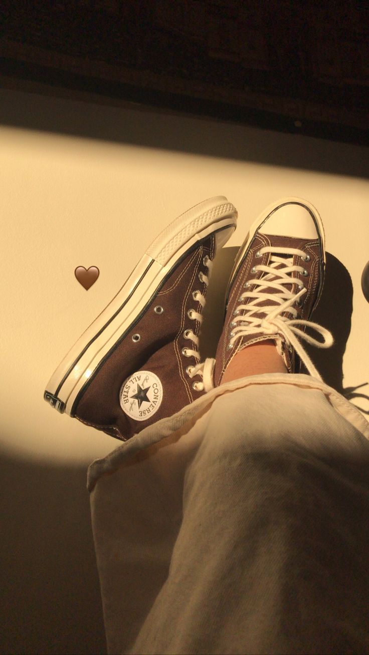 A person is standing on their feet with shoes - Converse