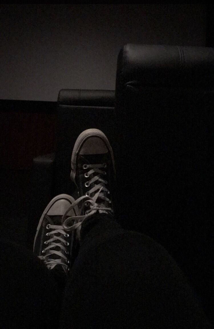 A pair of converse sneakers on a black leather chair - Converse