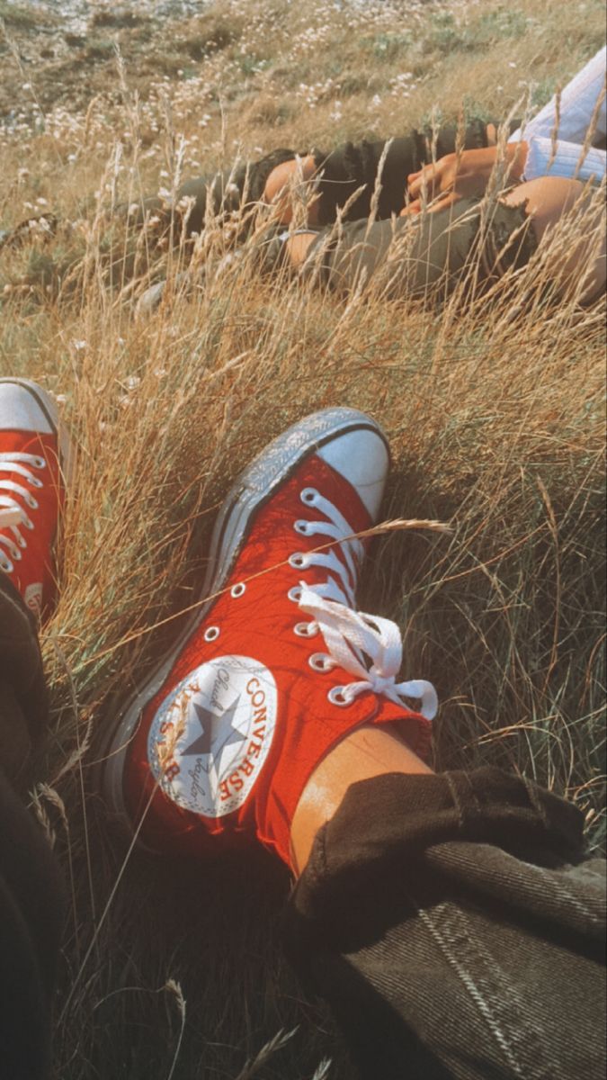 A person is laying down in the grass - Converse