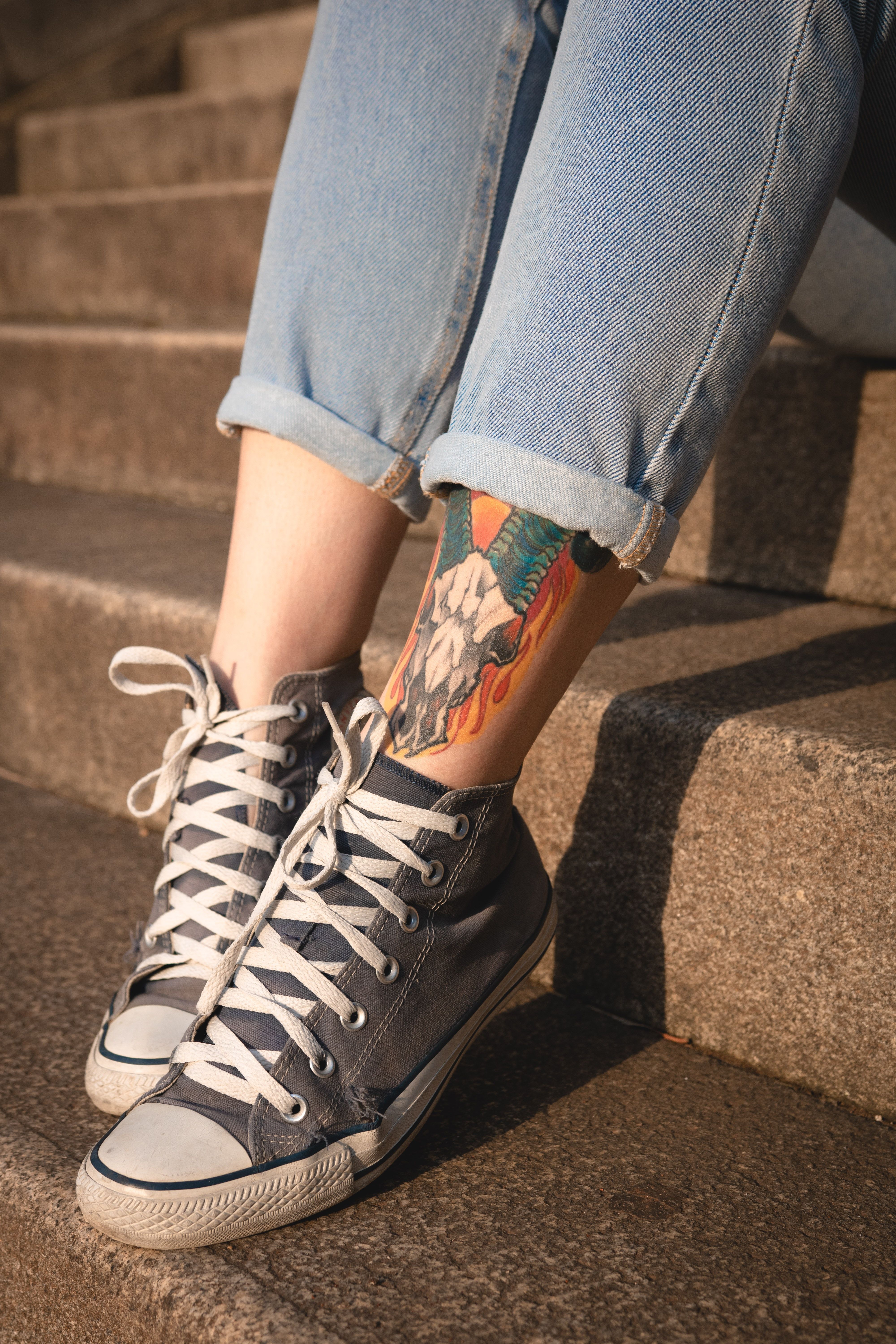 A woman with tattoos on her legs and feet - Converse, shoes