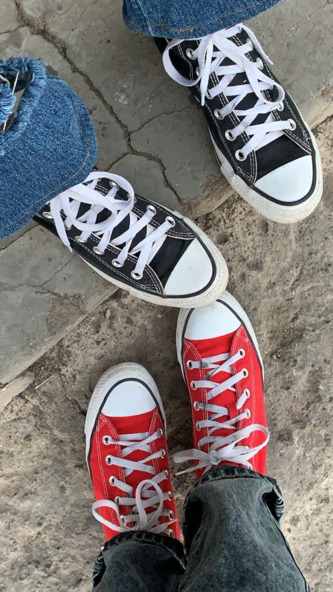 Three pairs of feet, each wearing a different color of Converse sneakers. - Converse