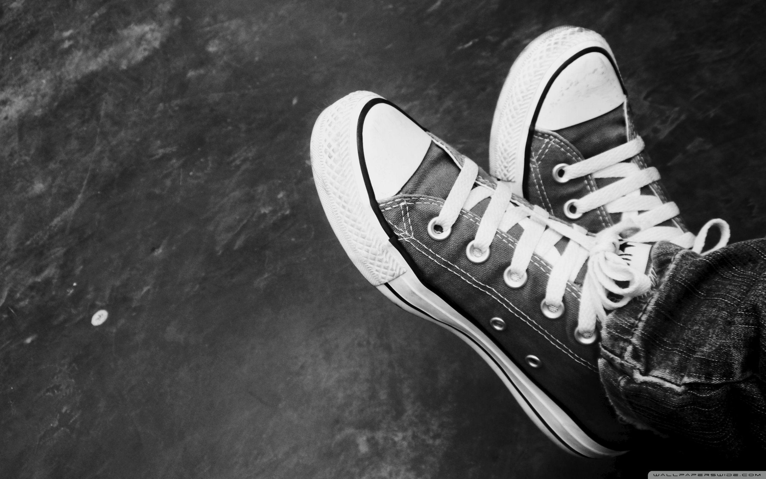 A black and white photo of someone's feet in converse shoes - Converse