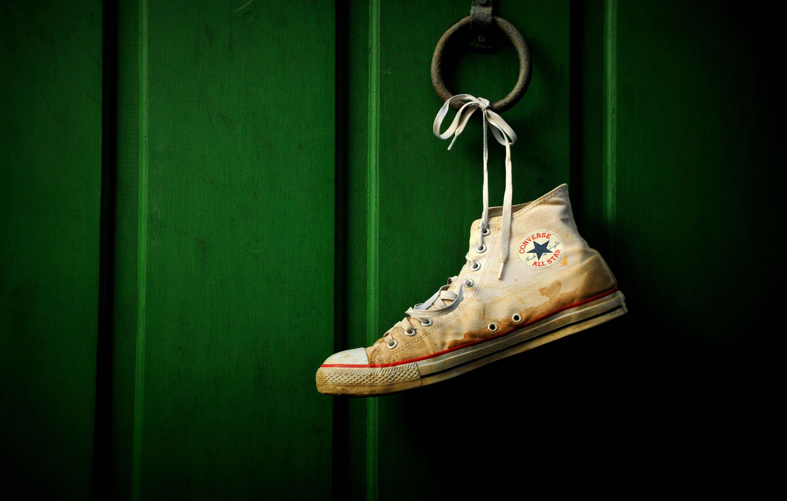 A shoe hanging on the wall of green - Converse