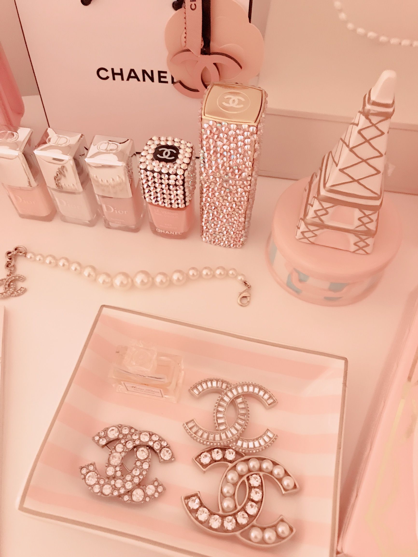 Pink Chanel items on a vanity, including a tray, earrings, and nail polish. - Gucci, Chanel