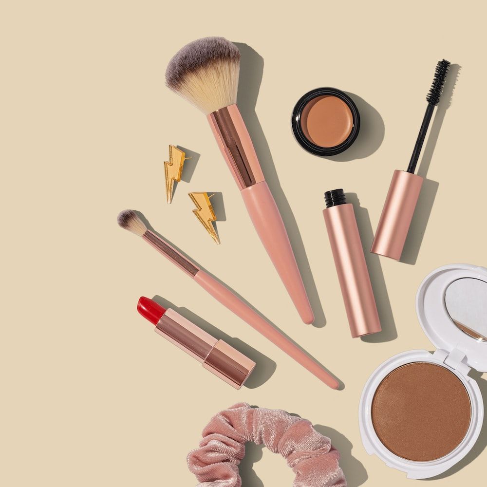 Various makeup products including a hair tie, brushes, lipstick, and eyeshadow - Makeup