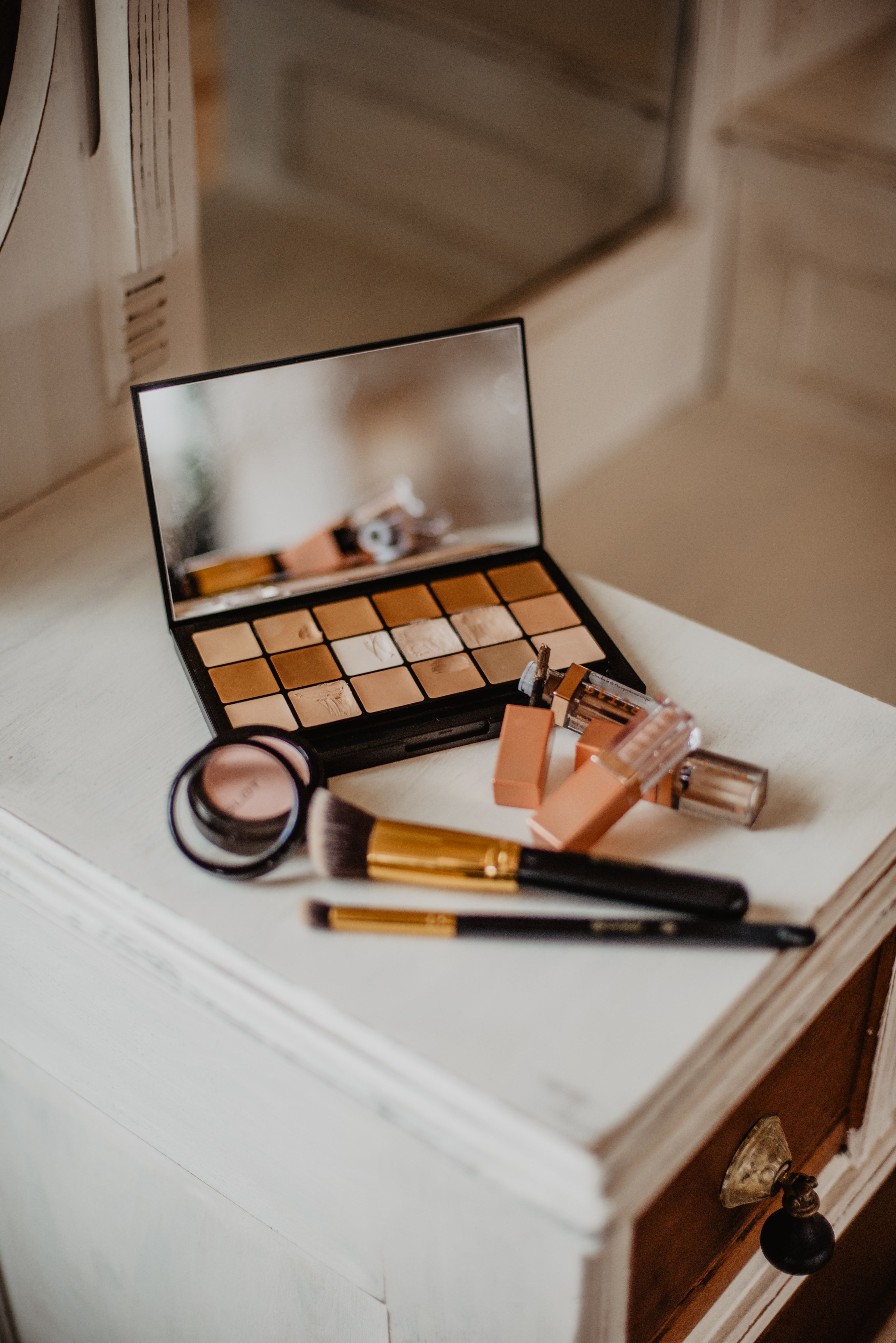 A makeup set on top of an old dresser - Makeup