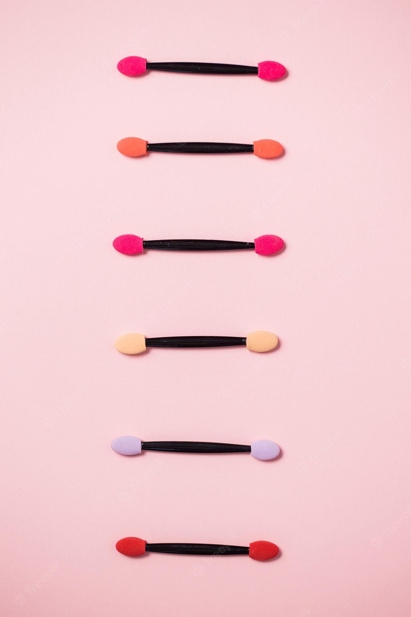 A row of colorful makeup applicators on a pink background - Makeup