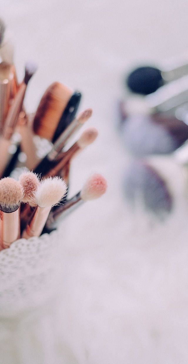 A cup full of makeup brushes on a white table - Makeup