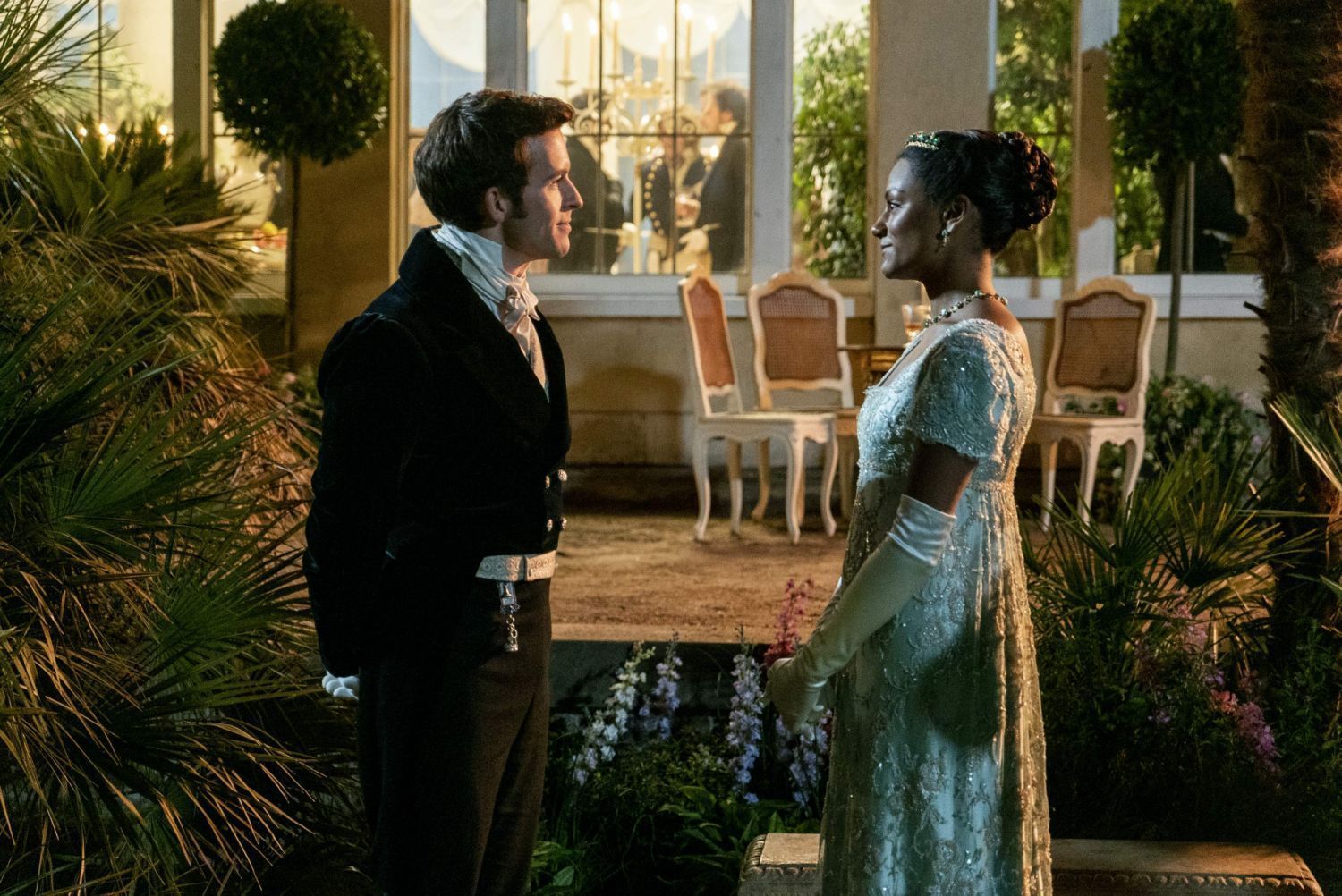 A man and woman in formal attire stand outside - Bridgerton